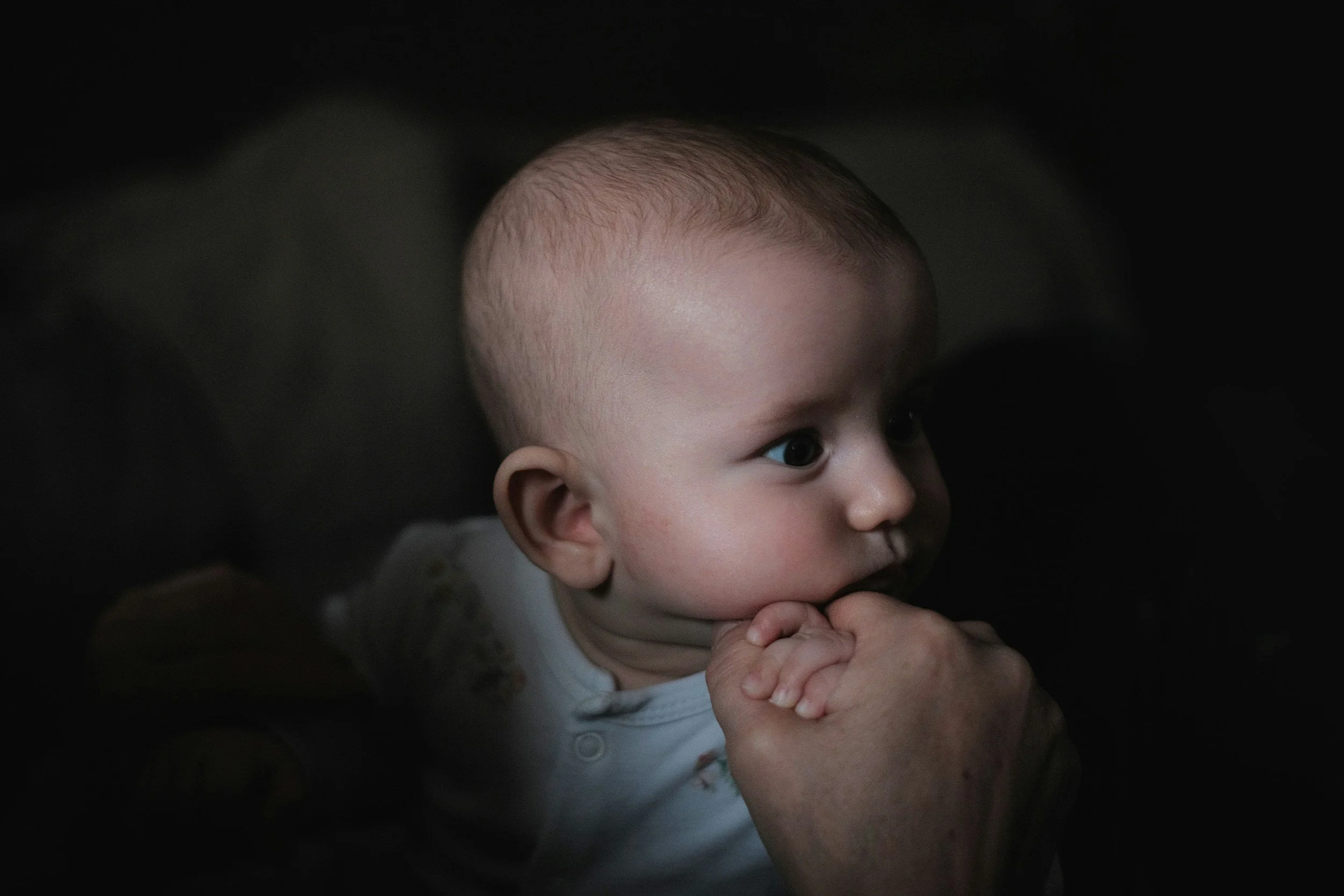 A close-up of a baby sleeping peacefully, face relaxed, in soft light
