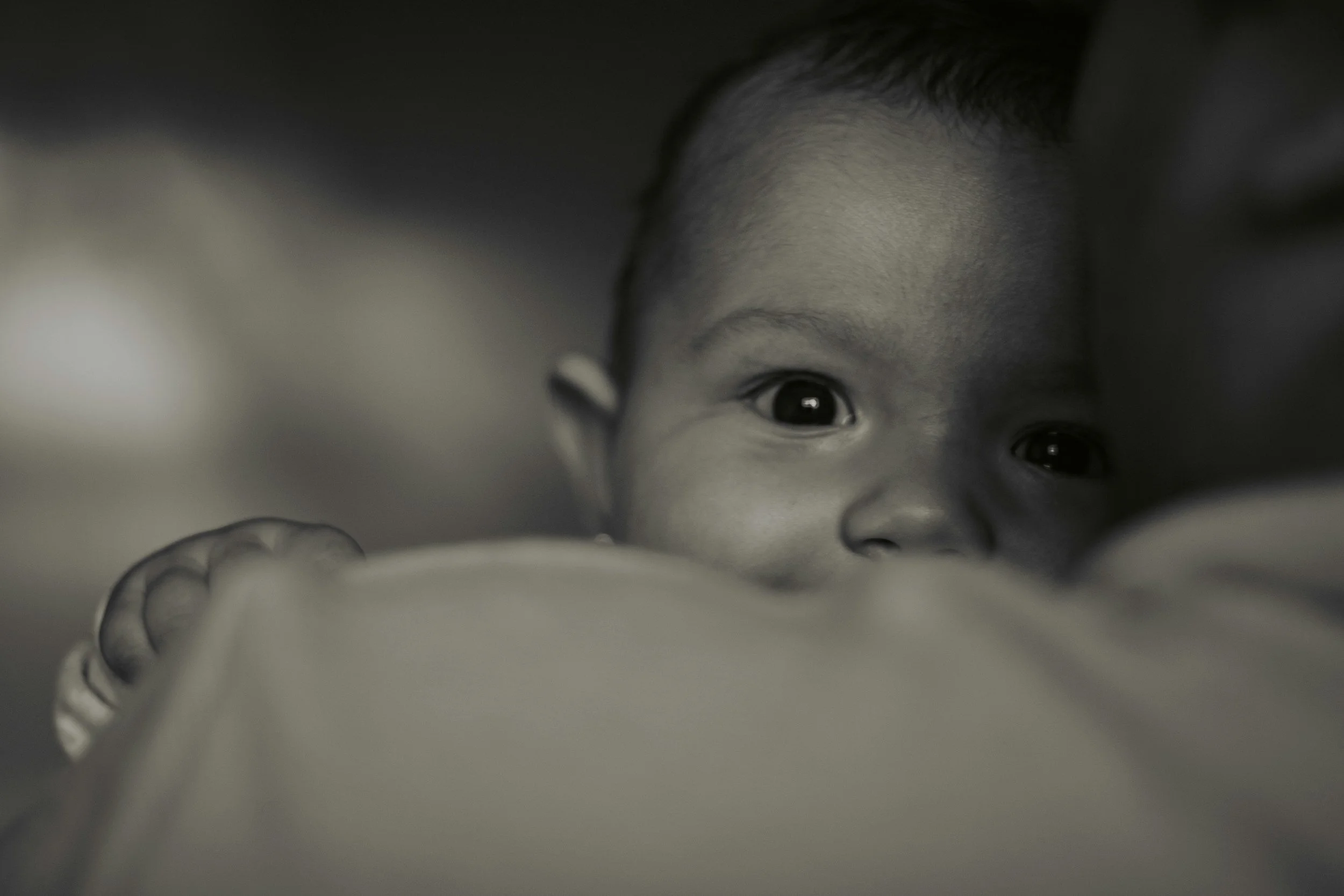A parent holding a sleepy baby in a calm, low-lit room at night