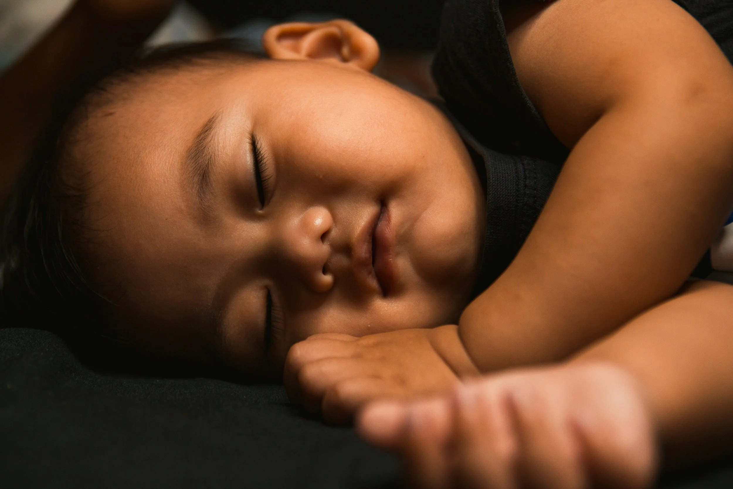 Sleeping baby with cheek resting on hands peaceful expression