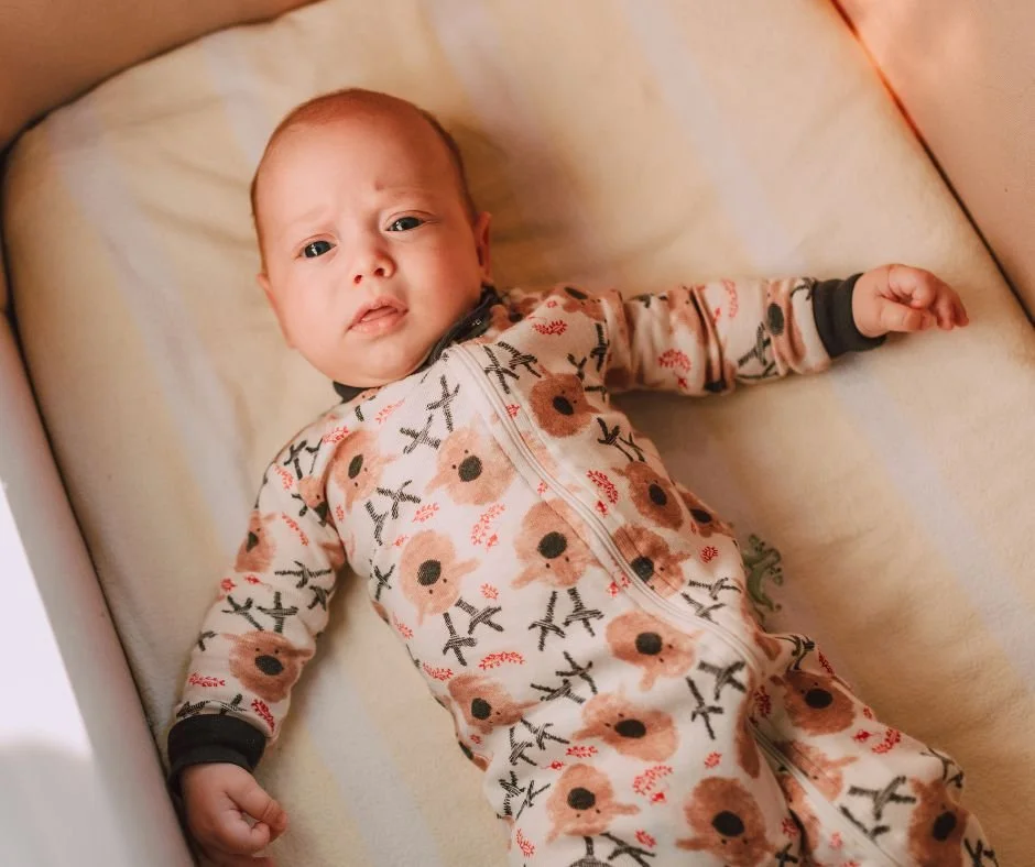 Wide awake baby lying in crib illustrating why babies wake at the end of a sleep cycle