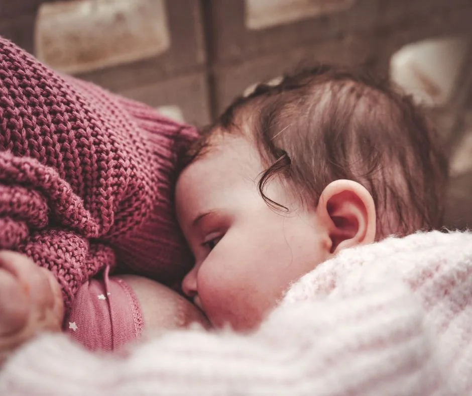 Parent breastfeeding baby to sleep at home in a calm, softly lit room