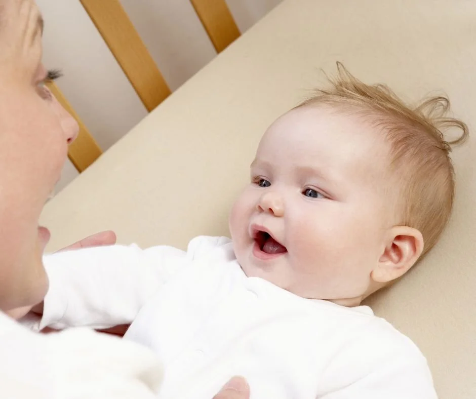 Content baby settling happily in the cot with mum close by