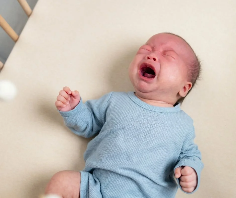 Upset baby crying in cot, struggling to settle to sleep alone