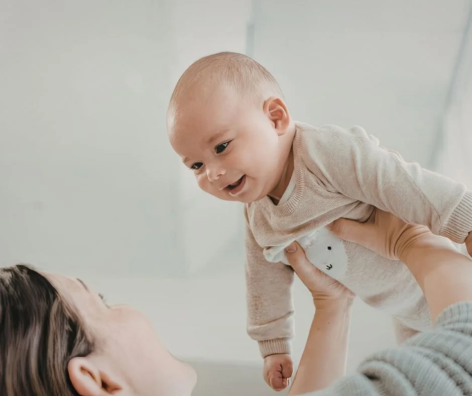 Parent lifting a giggling baby playfully overhead, an example of a sensory-seeking baby