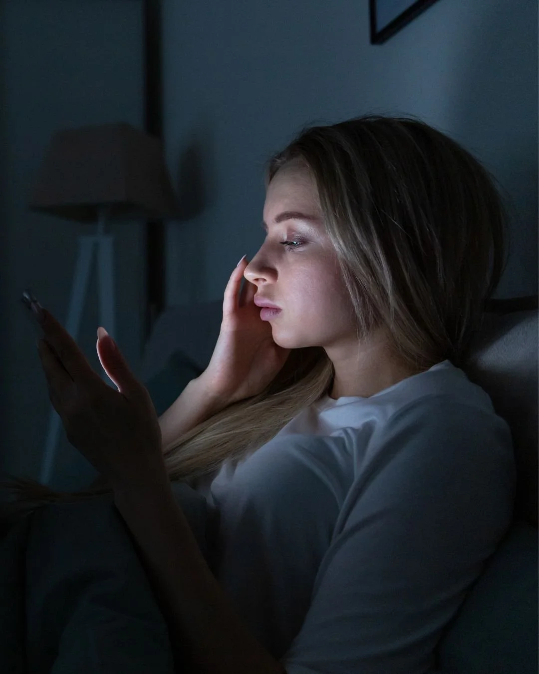 Exhausted mum scrolling phone at night during baby wake-up