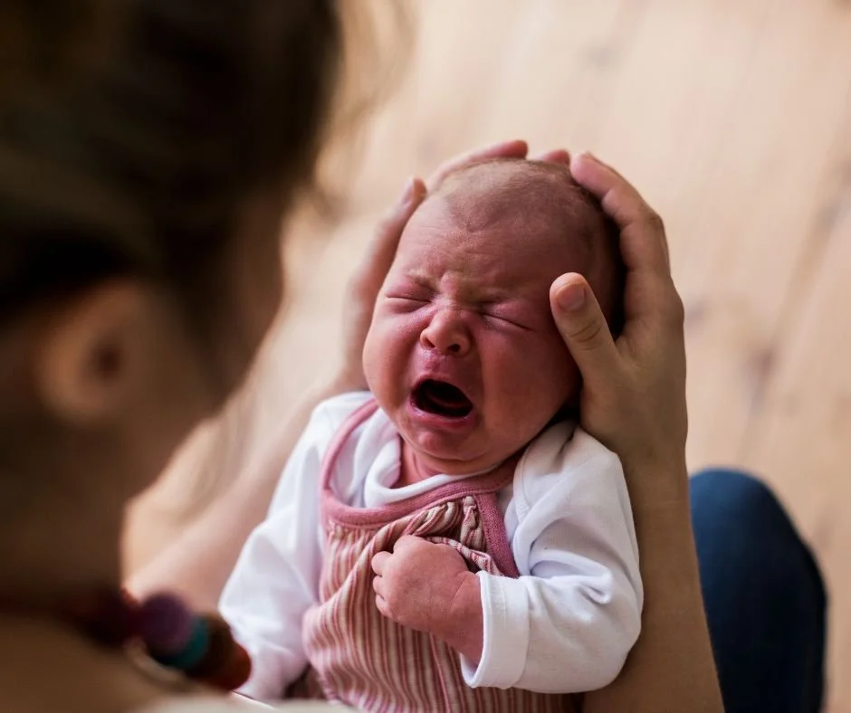 Mum holding a small crying baby and providing comfort