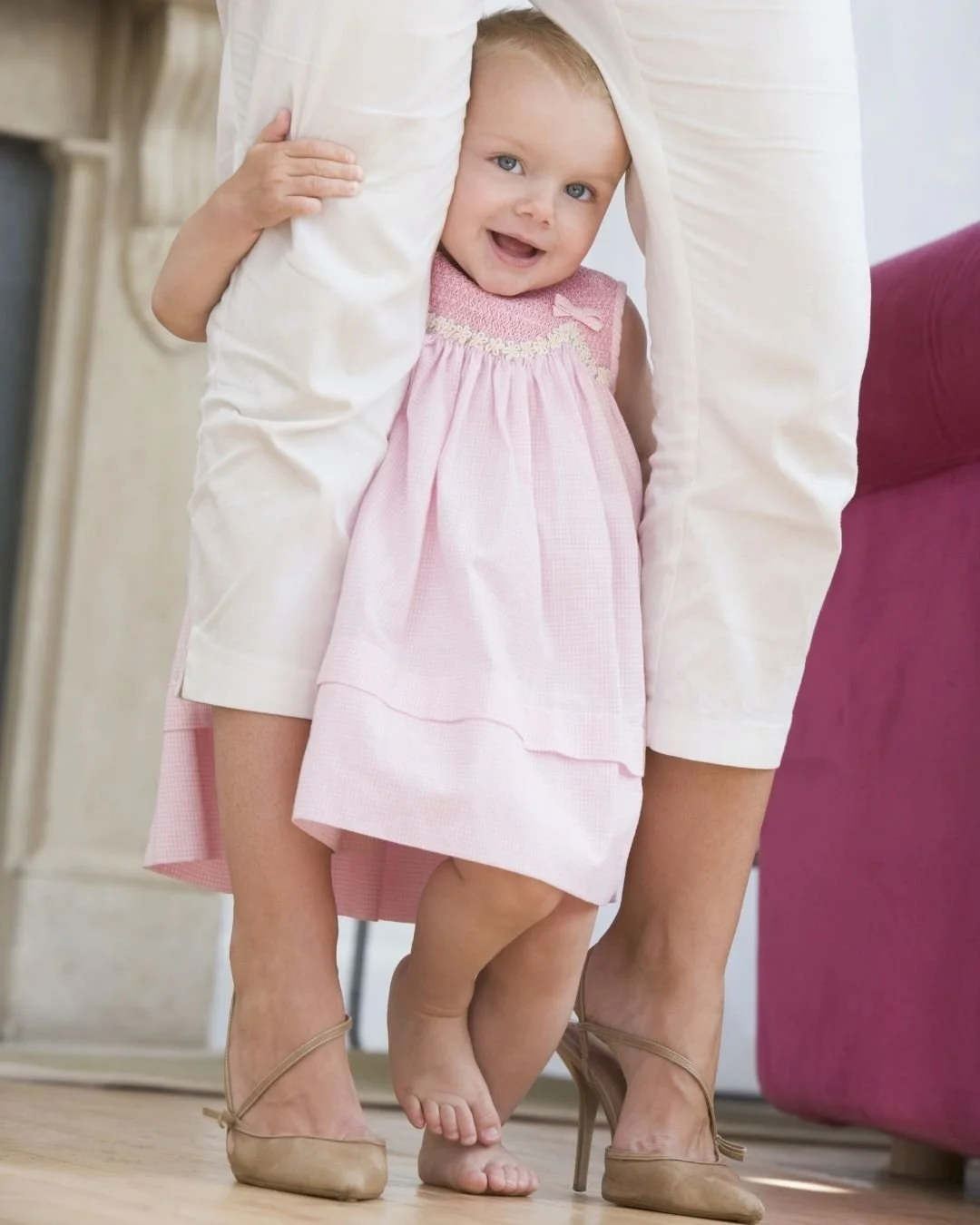 Cautious toddler hiding shyly behind parent's legs