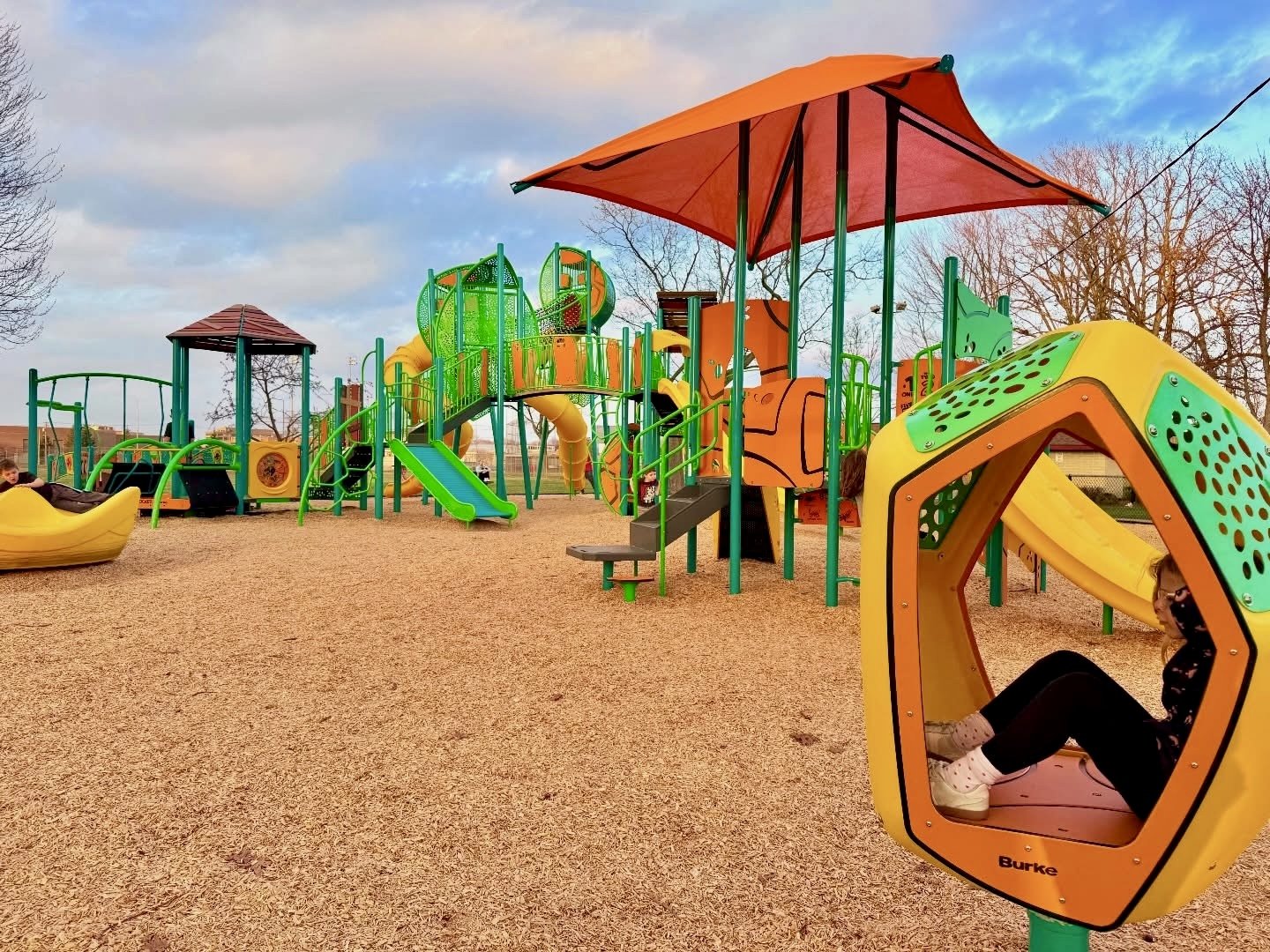 Large yellow, orange and green playground with mulch ground.