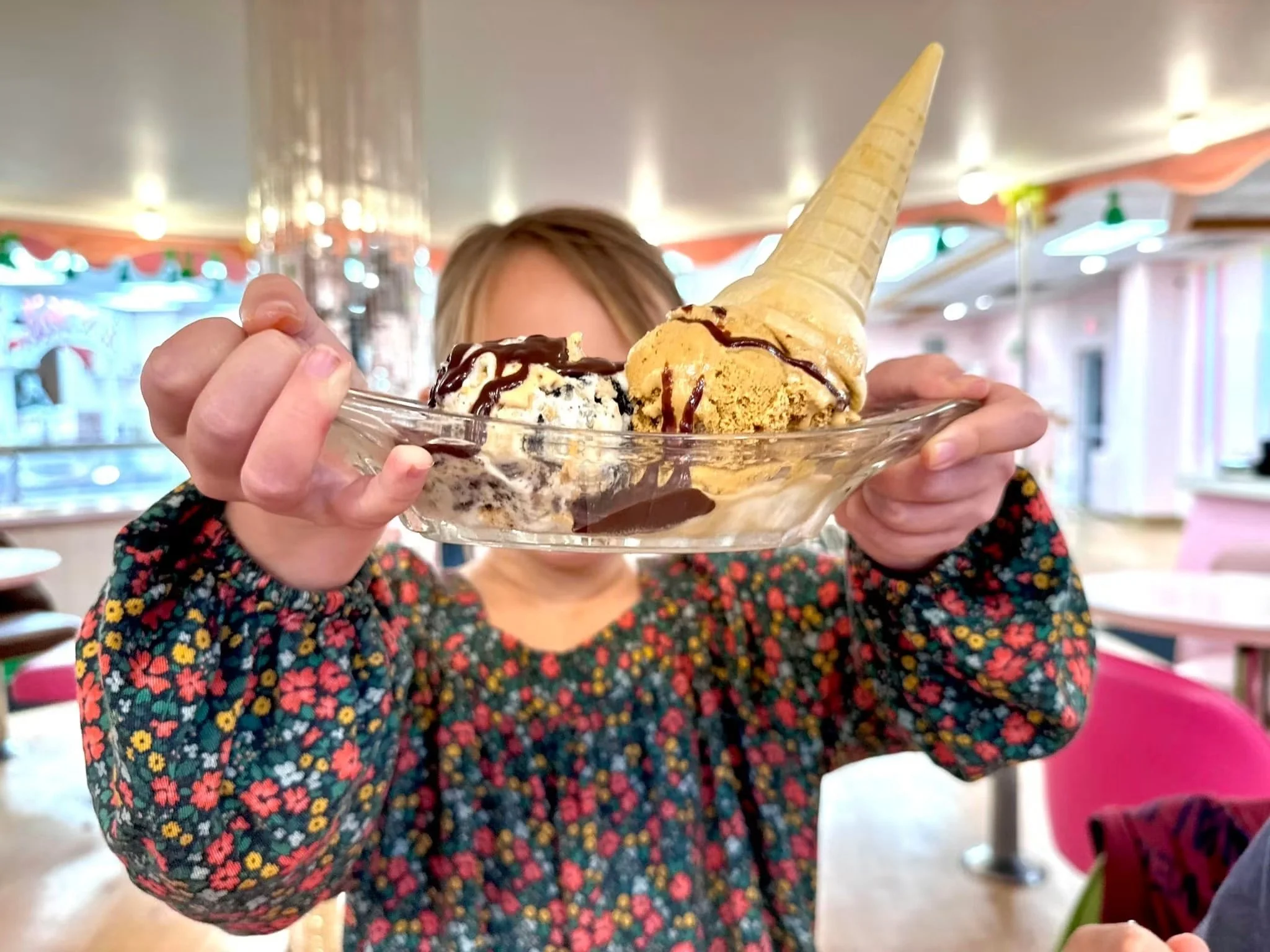 A little girl holding up an old fashioned bowl with ice cream in it