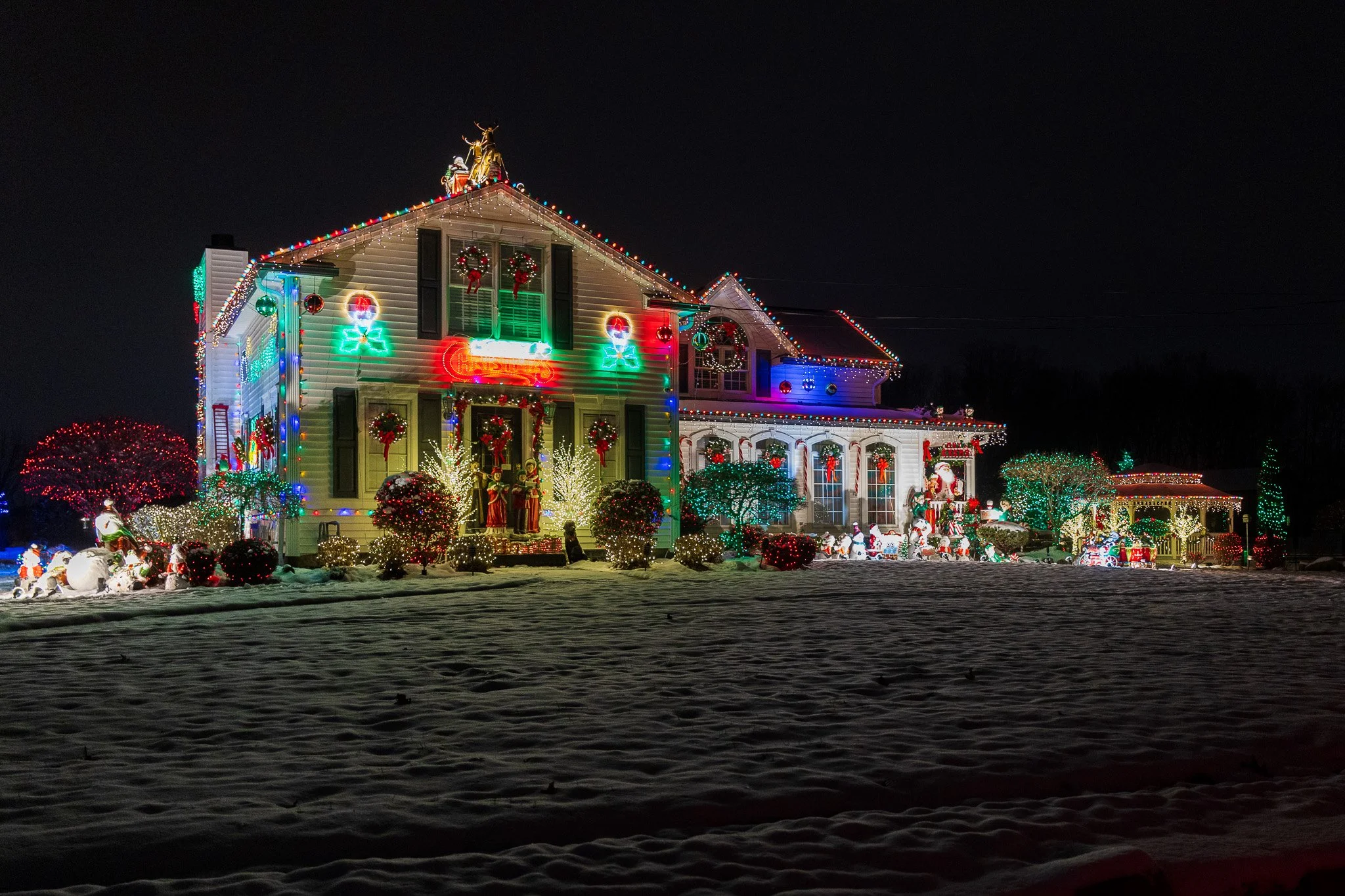 Large house beautifully decorated for Christmas with wreaths, candles, and Santa with his sleigh on the roof