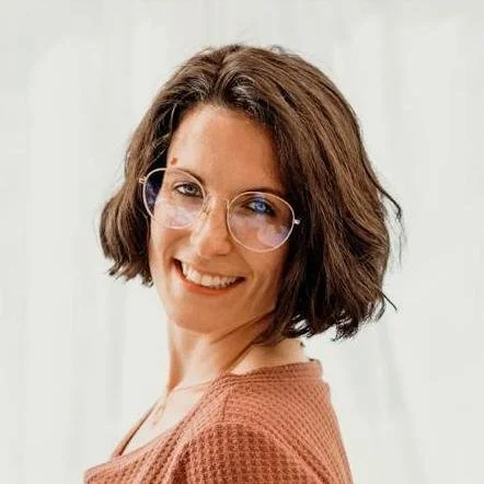 Frau mit halb langen braunen Haaren lächelt zufrieden in die Kamera als Portraitaufnahme.