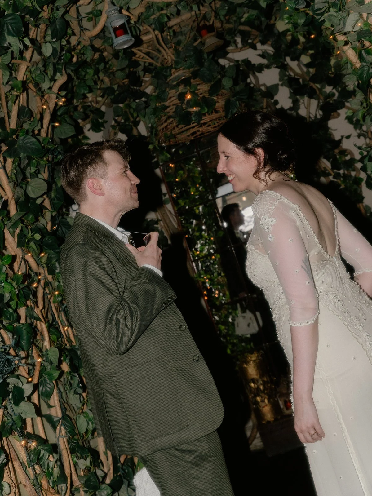 Bride and groom smiling, sharing a moment under a archway with foliage at Manhattan's High Line.