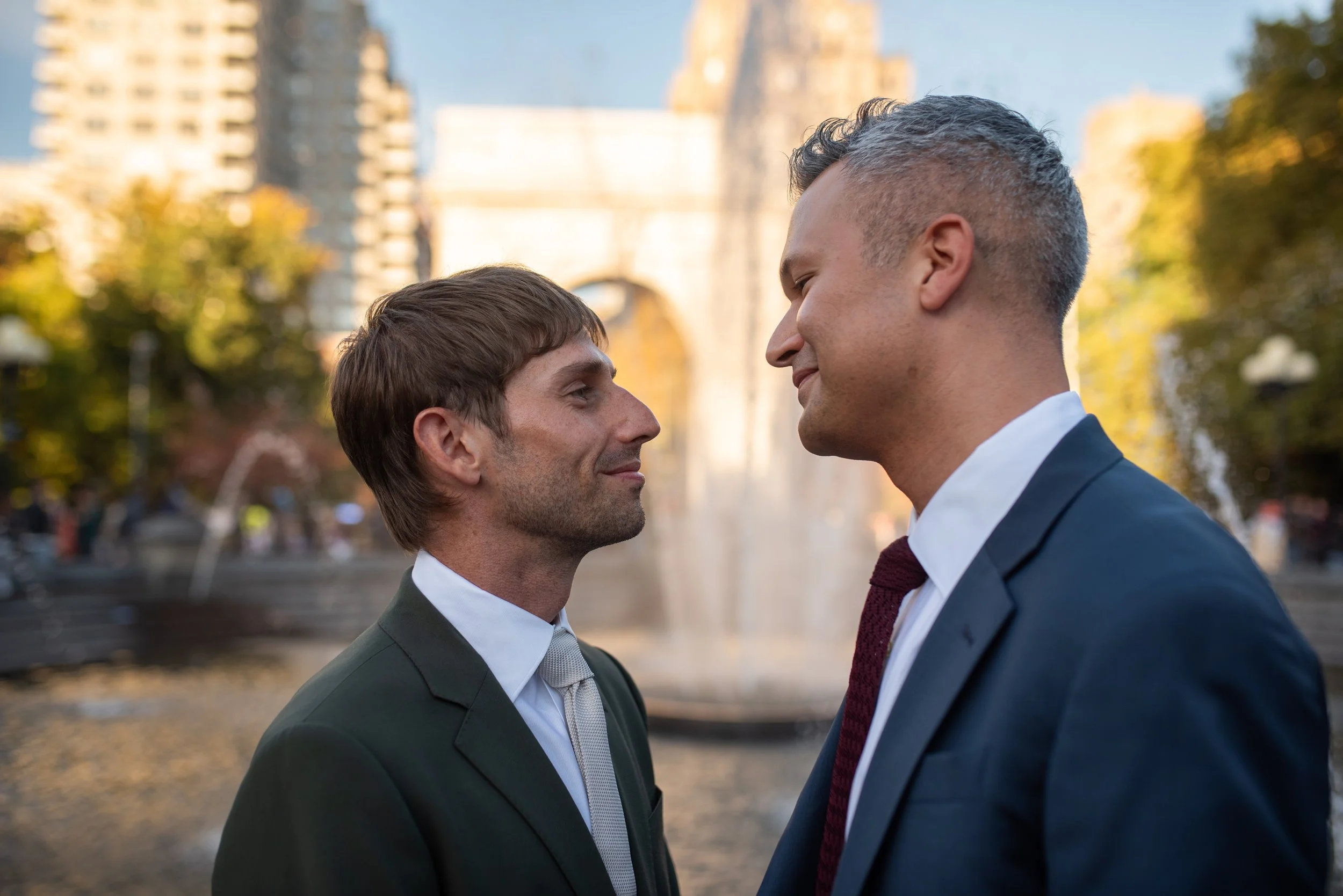 Two men gaze at each other in front of the arch and fountain at Washington Square Park