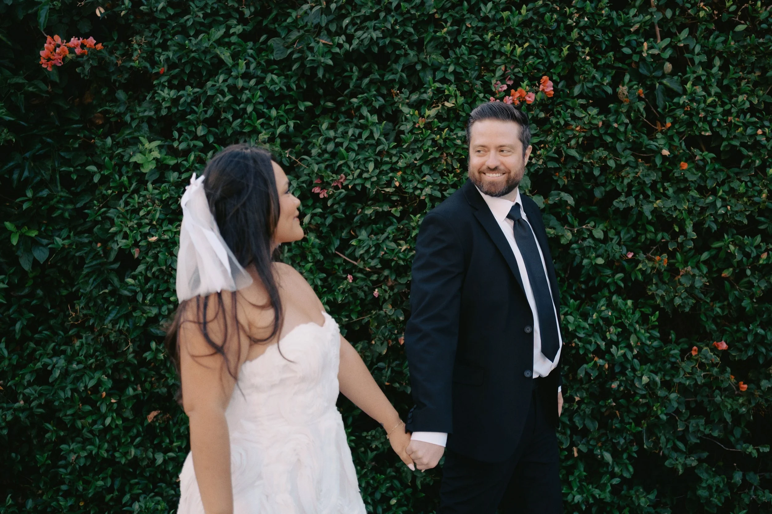 Bride and groom walking in front of hedges at the Fairmont Miramar & Gardens in Santa Monica before their Cakewalk elopement ceremony.