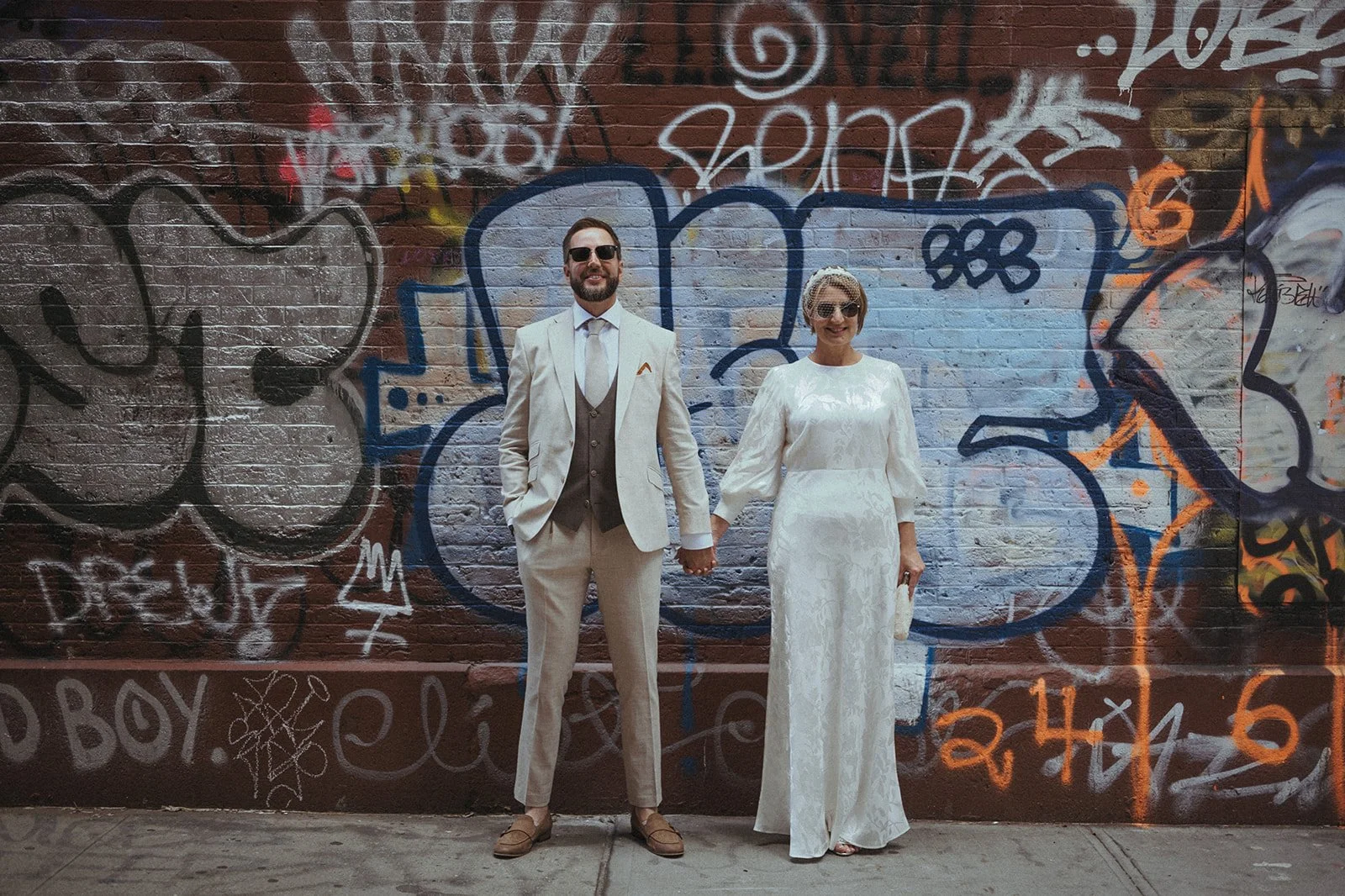Bride and groom standing in front of graffiti in SoHo after their Cakewalk elopement ceremony.