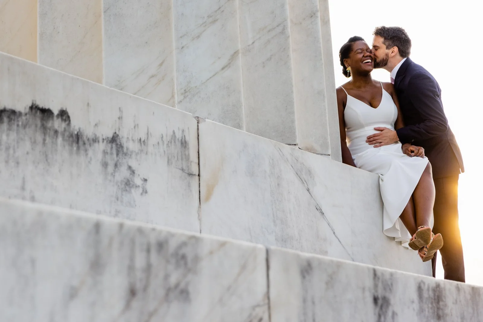 Bride and groom sharing a laugh on the marble steps of the Lincoln Memorial at golden hour, elopement Washington DC.