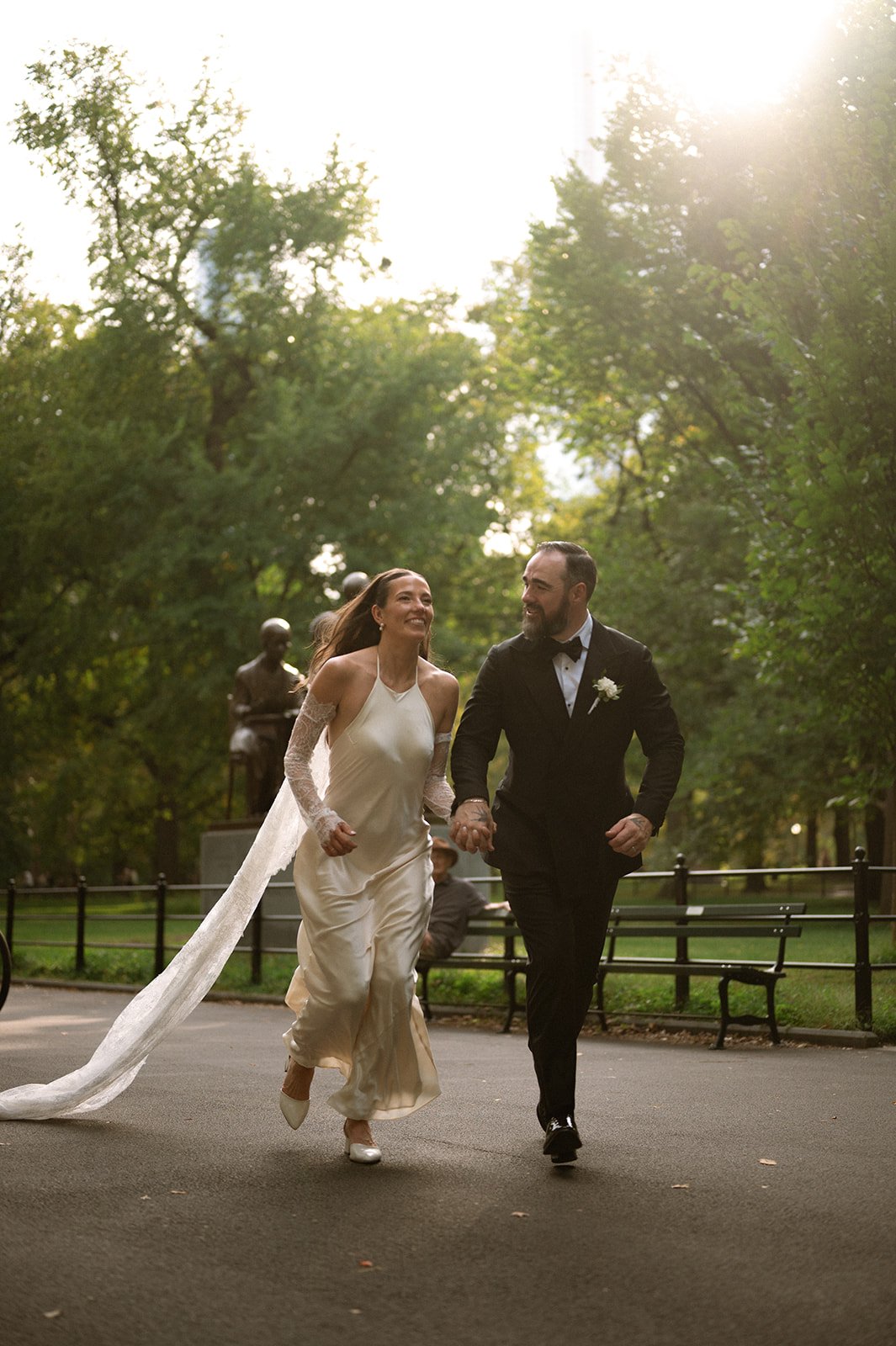 Bride and groom running down a path in Central Park after their Cakewalk micro wedding.