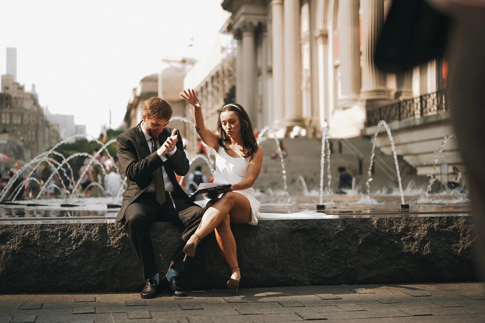 Bride and groom sitting on a fountain at the Met Museum of Art signing their marriage license after their Cakewalk elopement.