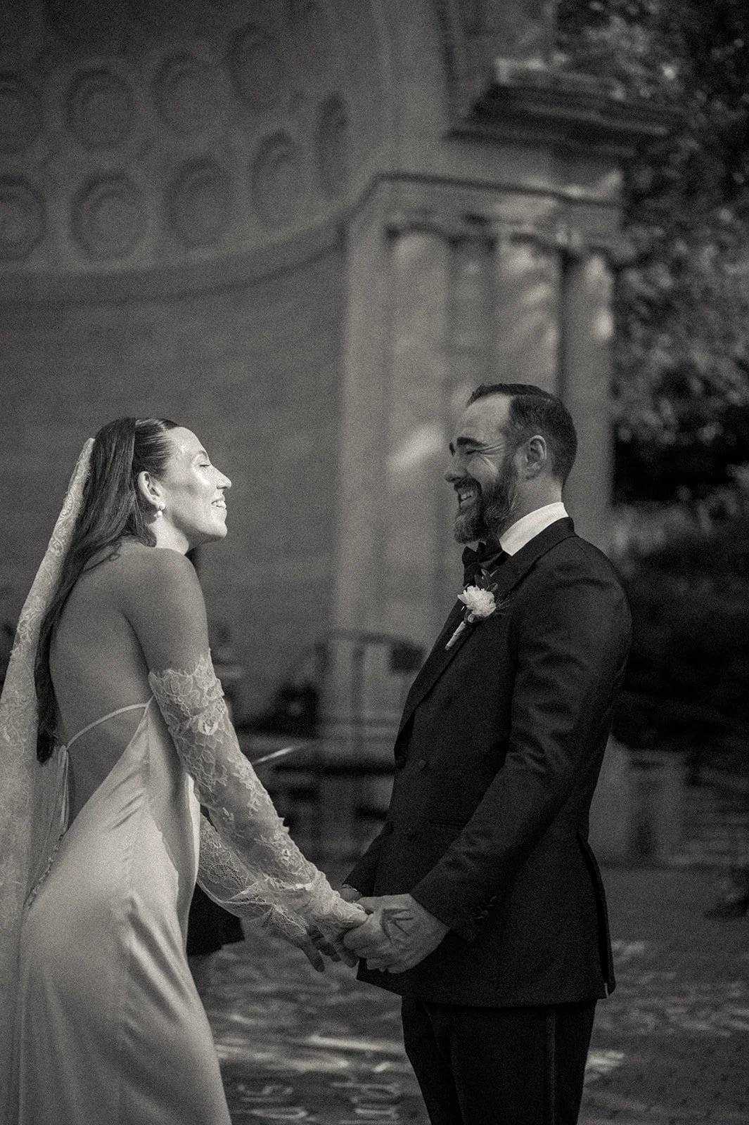 Bride and groom holding hands in front of Naumburg Bandshell behind them at their Central Park micro wedding by Cakewalk.