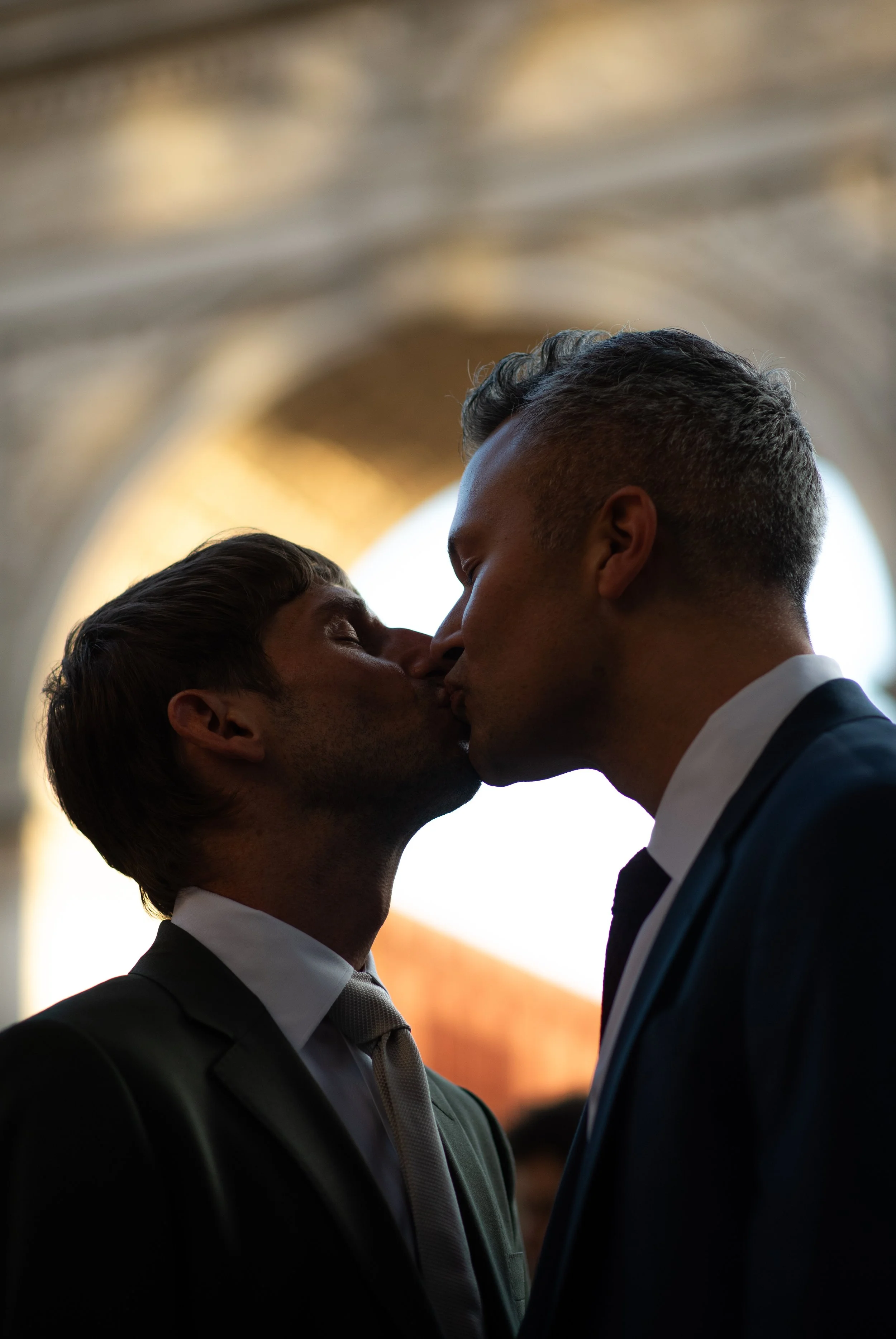 Two men kissing in Washington Square Park with the arch behind them before their Cakewalk elopement ceremony.