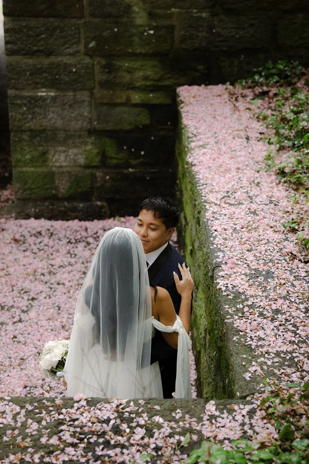 Newlyweds embracing in pink flower petals during their NYC elopement ceremony