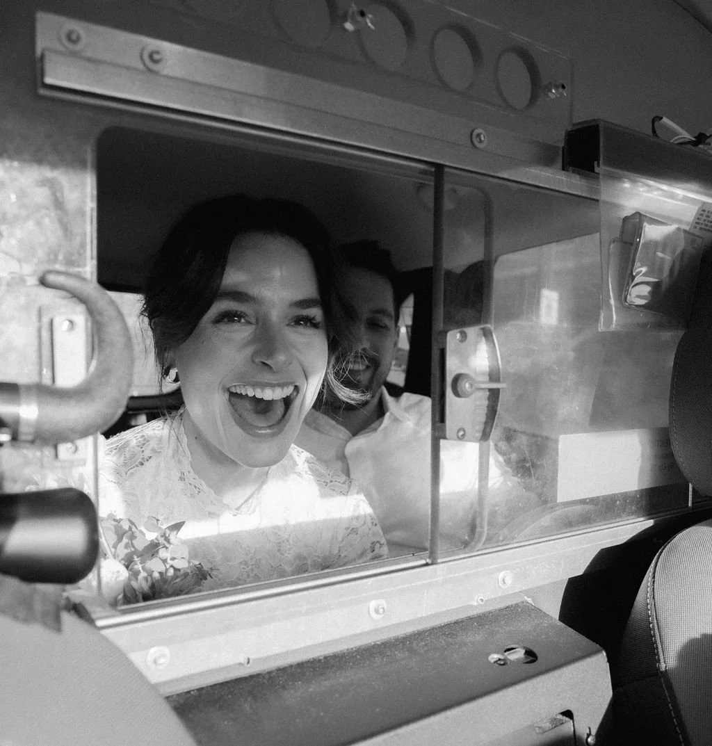 A woman and a man smiling inside a vehicle's delivery window.