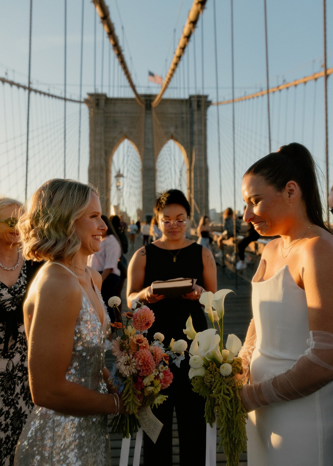 Sjaan and Megan exchanging vows at sunrise on the Brooklyn Bridge surrounded by their small group of guests.