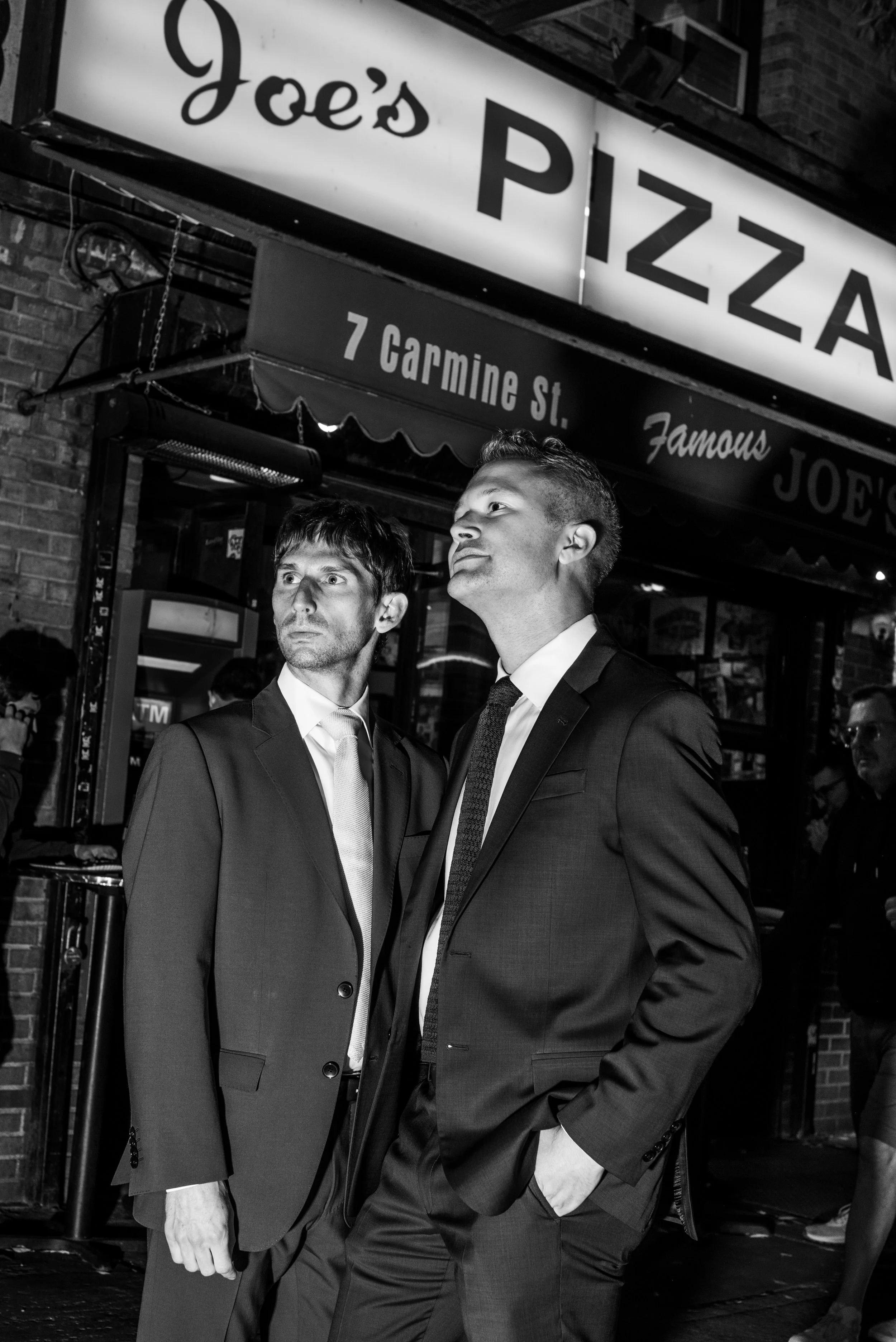 Two men walking standing outside Joe's Pizza on the way to their Cakewalk elopement ceremony.