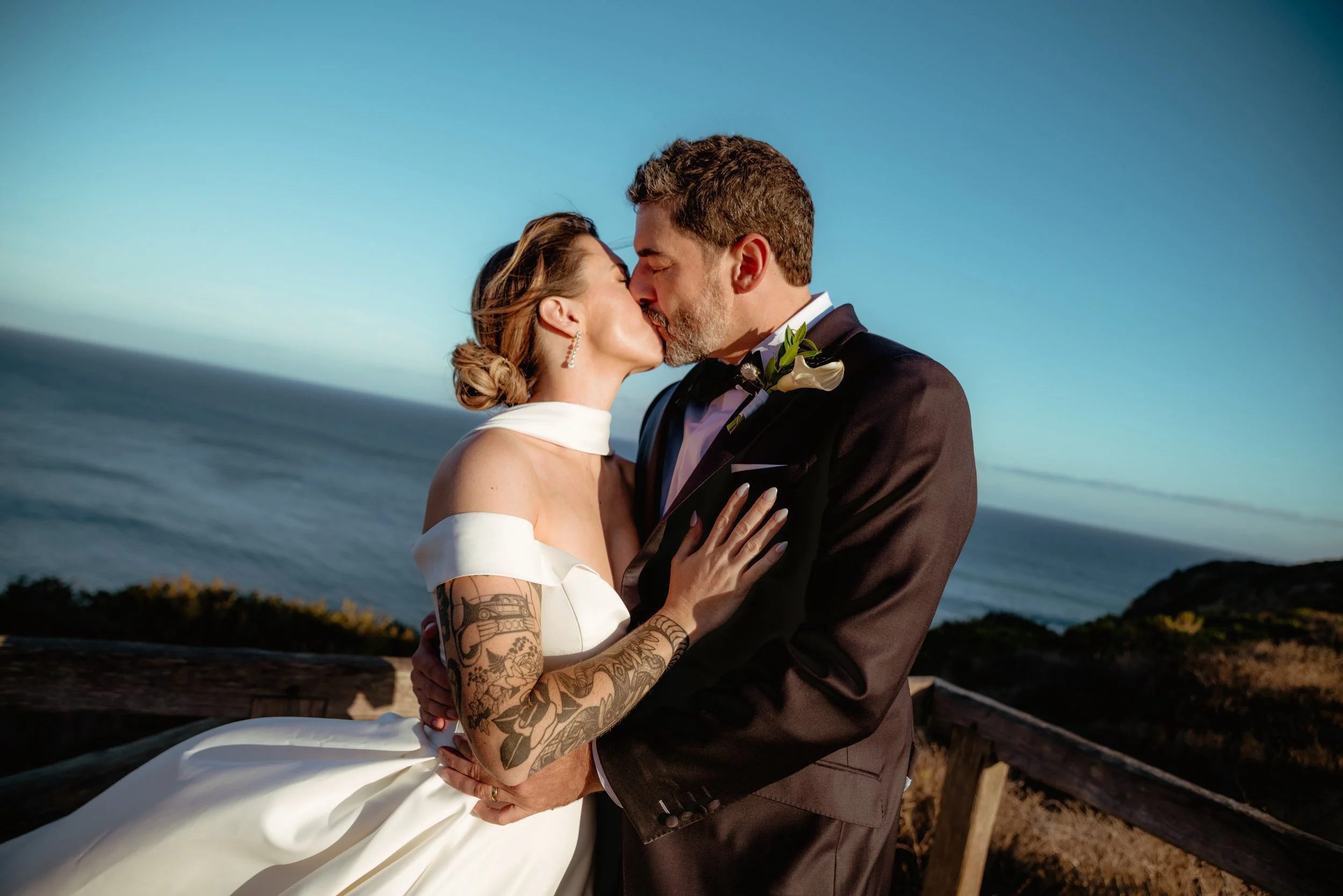 Bride and groom kissing with the ocean behind them at Point Dume after their Cakewalk micro wedding.