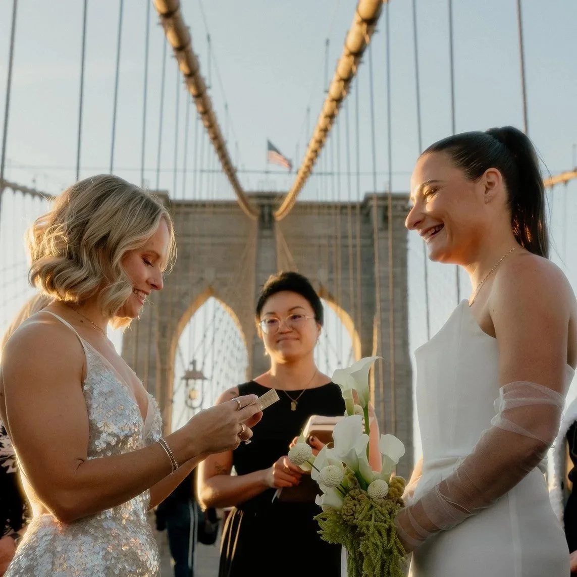 Two brides exchanging vows on the Brooklyn Bridge during their NYC elopement ceremony