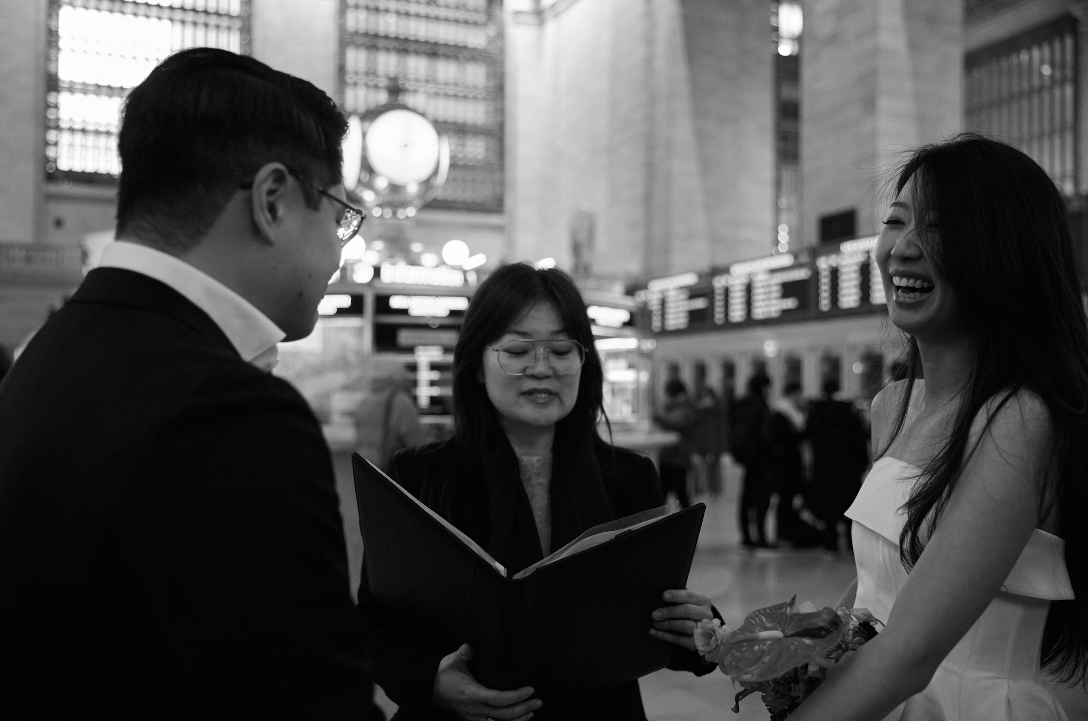 Coupel smiles during their Grand Central Station elopement ceremony as an officiant leads them.