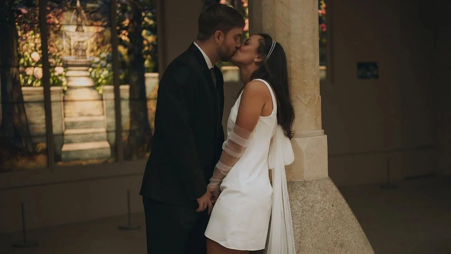 Kyla and Zach sharing a quiet kiss near the stained-glass gallery inside the Met.