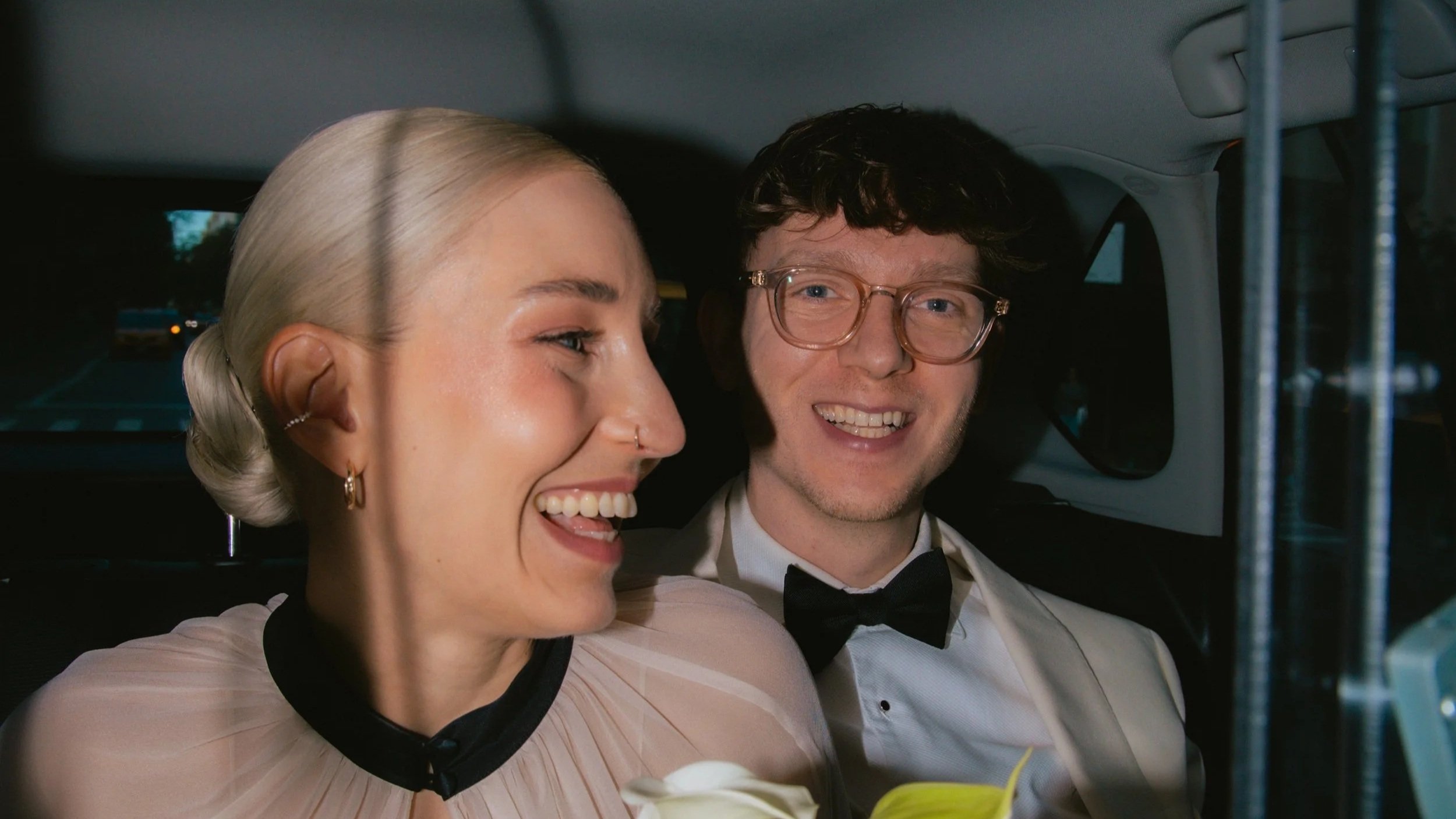 Candid photo of a bride and groom smiling in an NYC taxi after their elopement ceremony in Central Park.