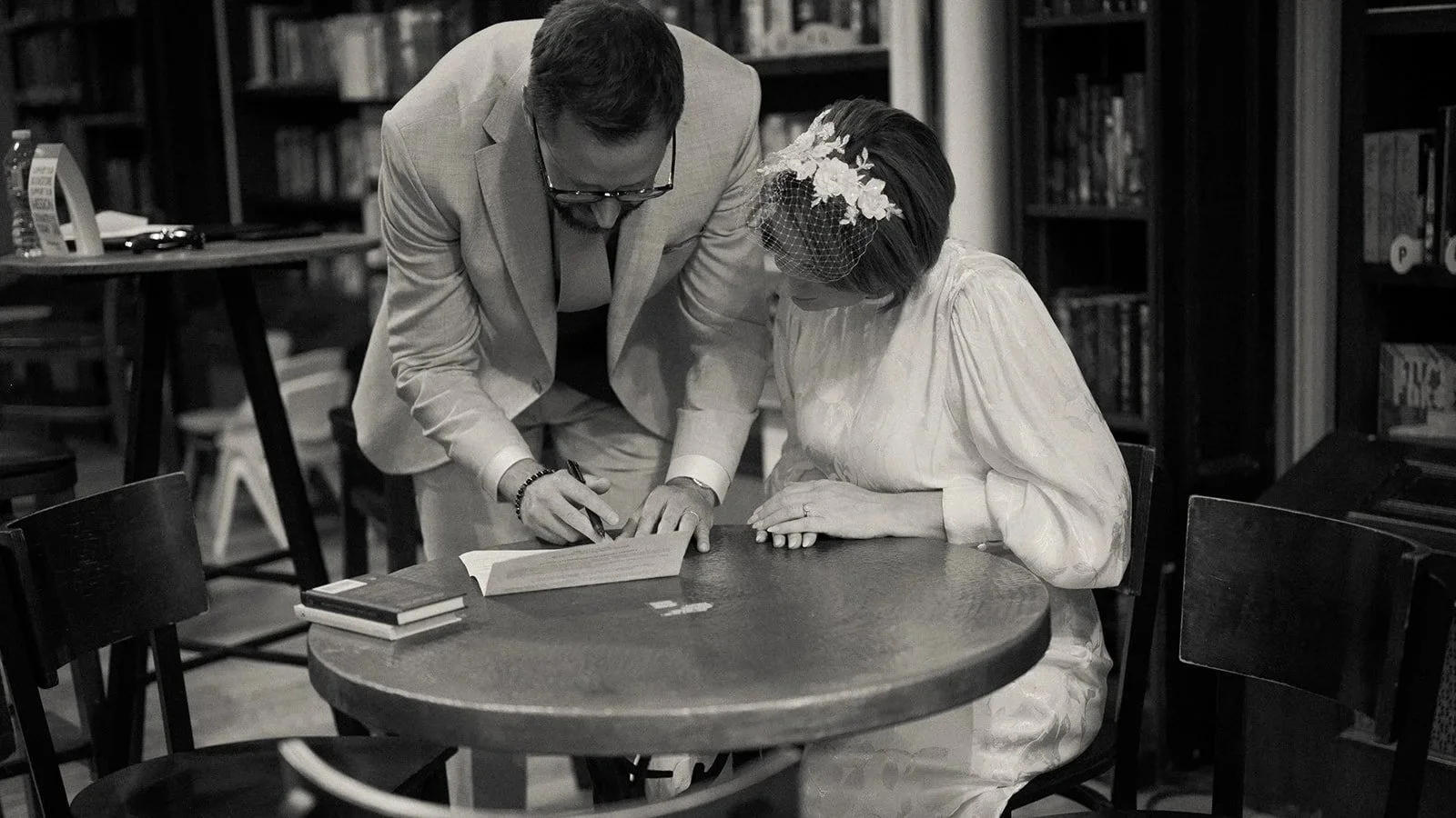 Documentary style photography of couple getting eloped signing their marriage license at Housing Works bookstore in NYC with Cakewalk.