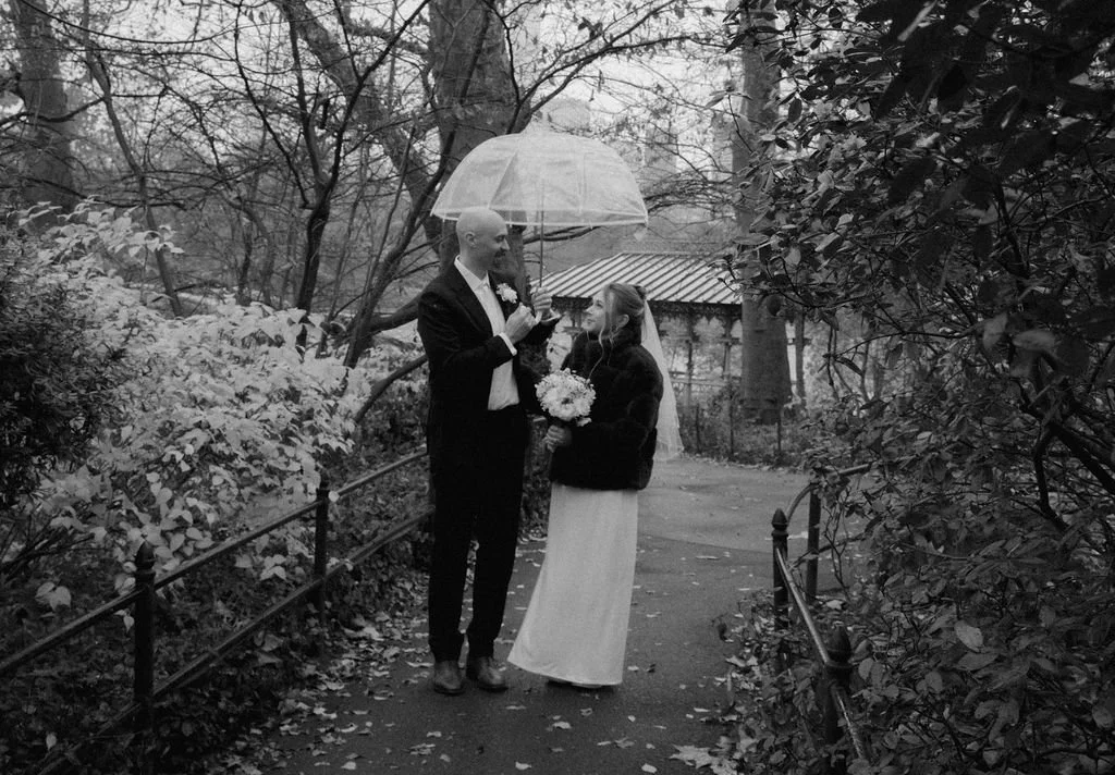 Rainy Central Park elopement with couple sharing an umbrella after their ceremony