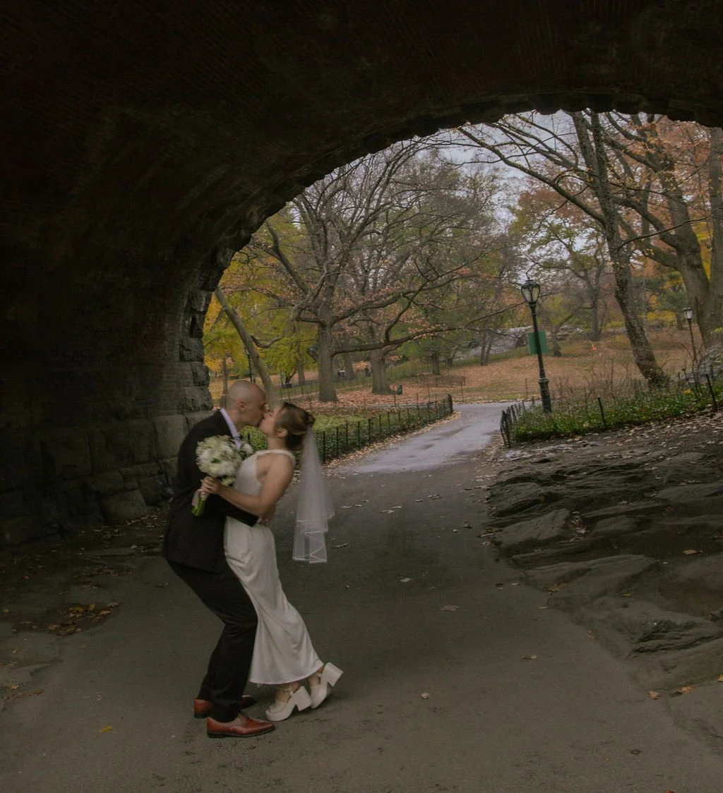Newly married couple kissing under a bridge during a fall Central Park elopement