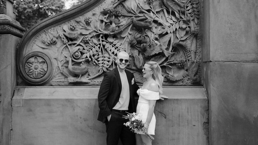 Chloe and Sam in front of a carved stone wall at Central Park after their Wagner Cove elopement.