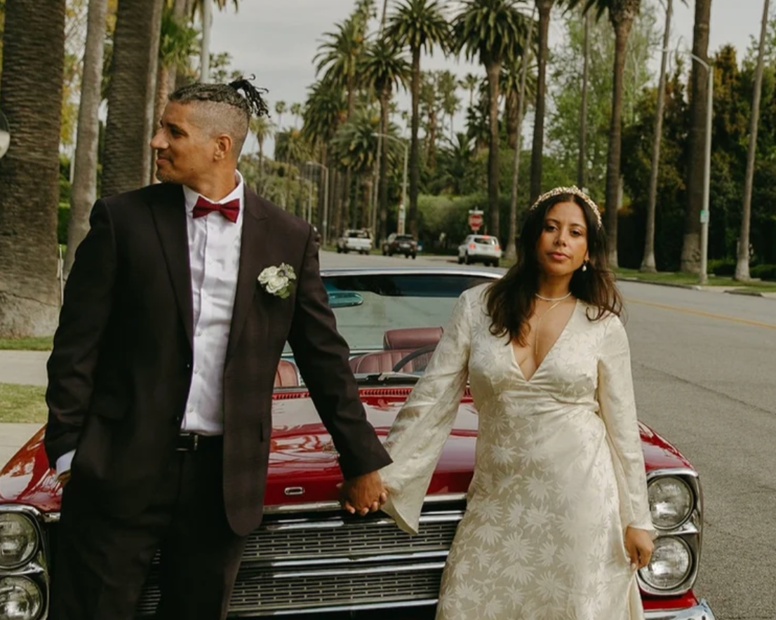 Couple with a vintage red convertible on a palm-lined LA street
