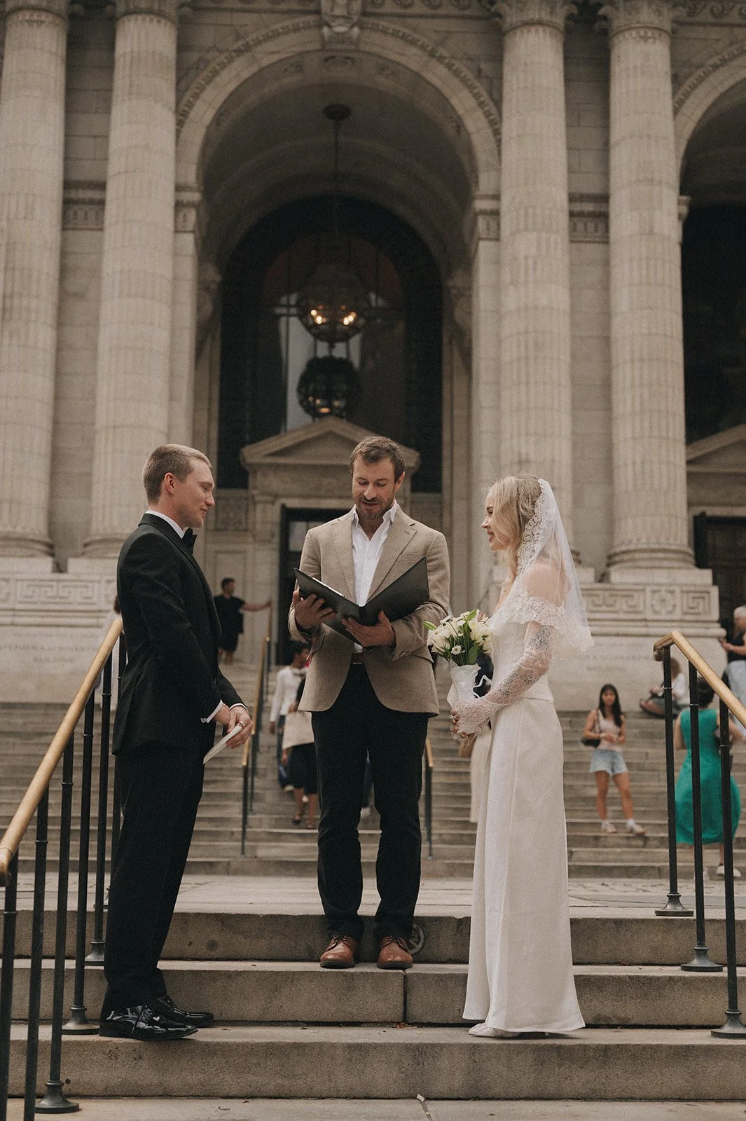Couple eloping with their officiant in front of the New York Public Library on the steps.