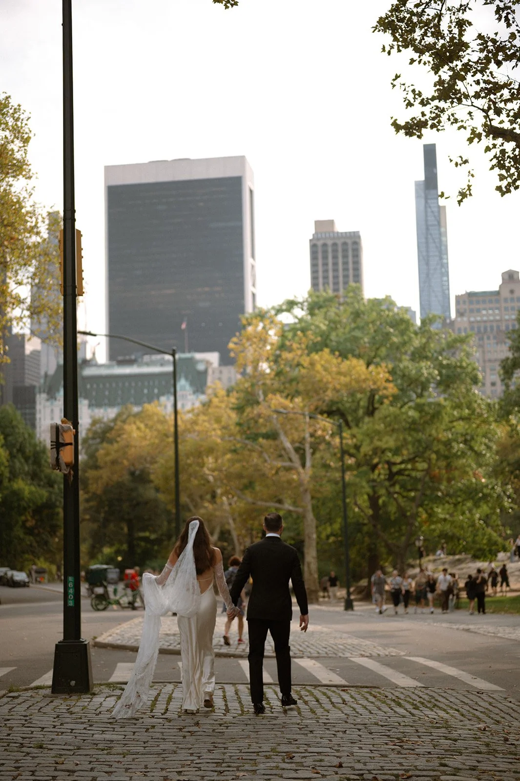 Bride and groom walking out of Central Park toward the New York City skyline after their Cakewalk micro wedding.