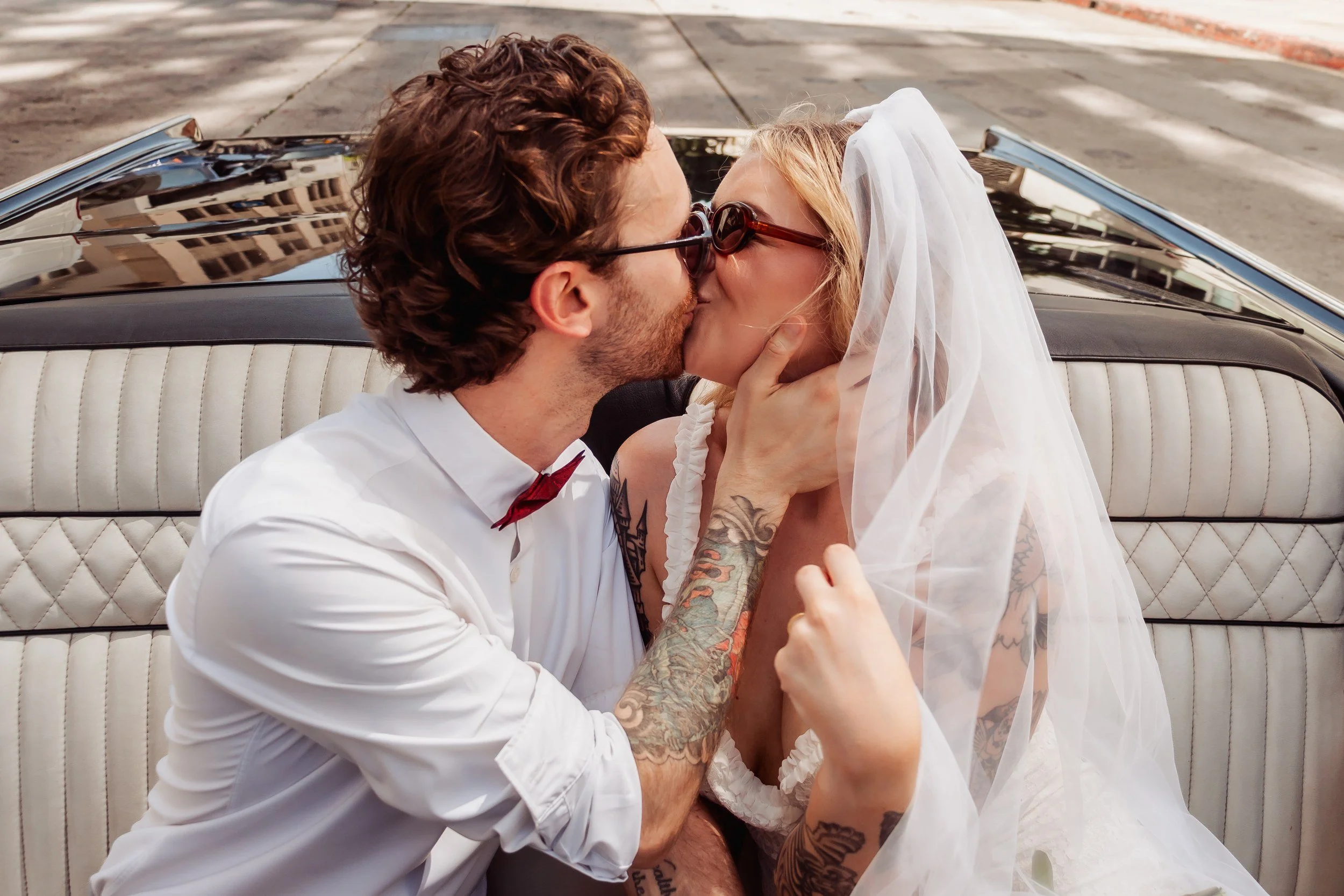 Newlyweds kissing in a vintage Lincoln convertible during a Los Angeles elopement.