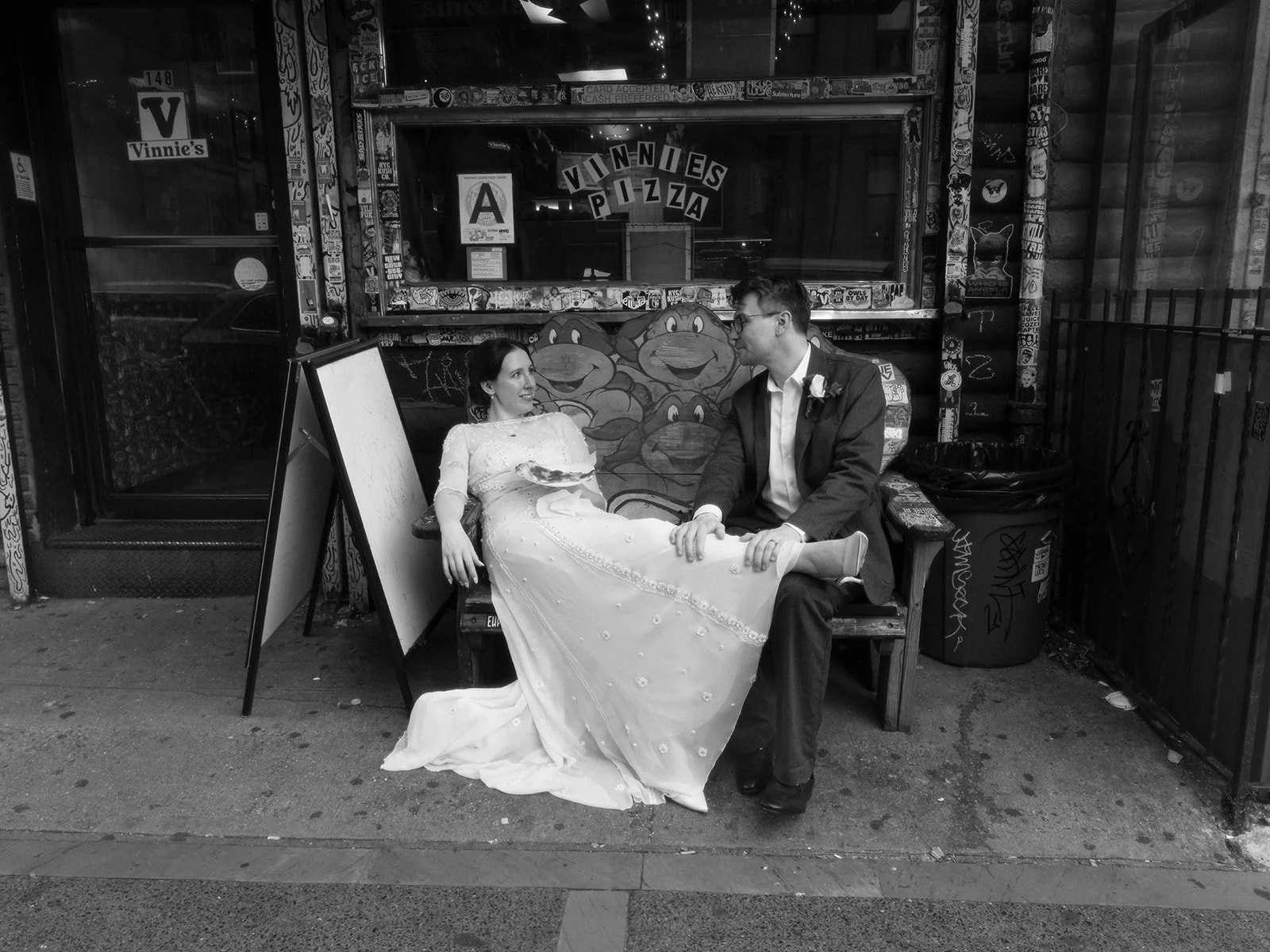 Bride and groom relaxing outside Vinnie's Pizzeria, holding a slice after their Cakewalk elopement.
