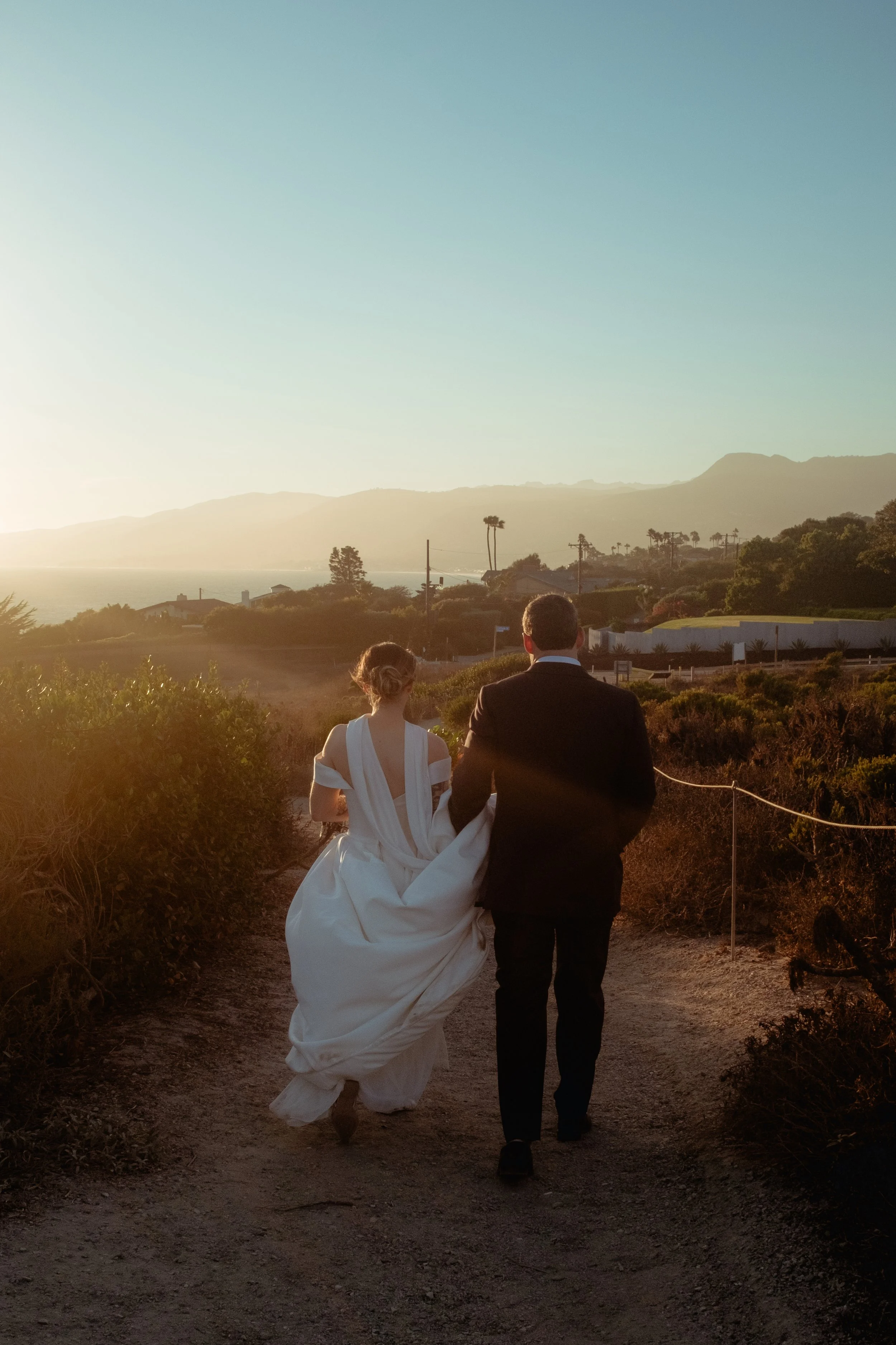 Bride and groom running down the trail at  Point Dume at sunset after their Cakewalk micro wedding.