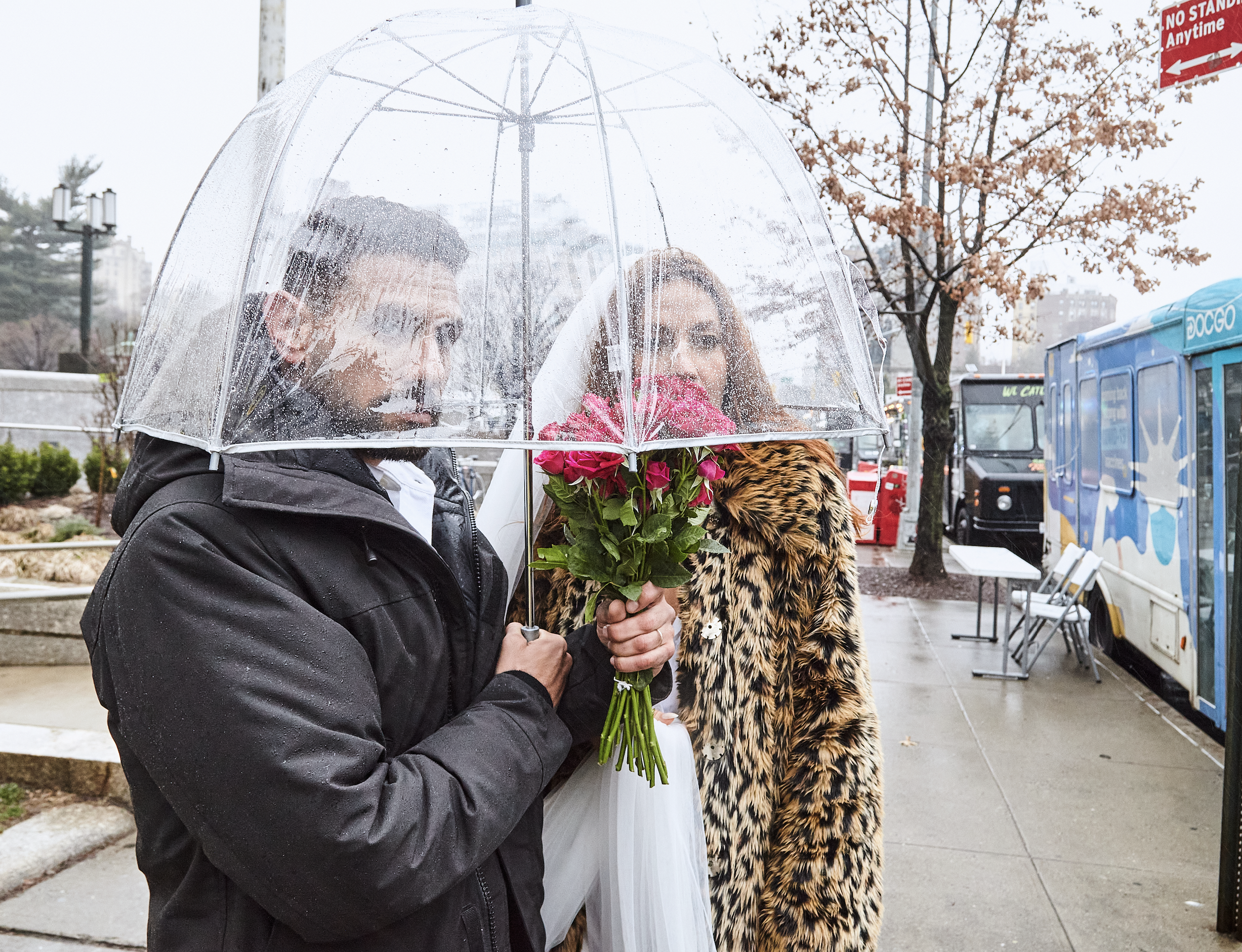 Bride and groom standing under an umbrella, holding flowers after their Cakewalk ceremony in Brooklyn.