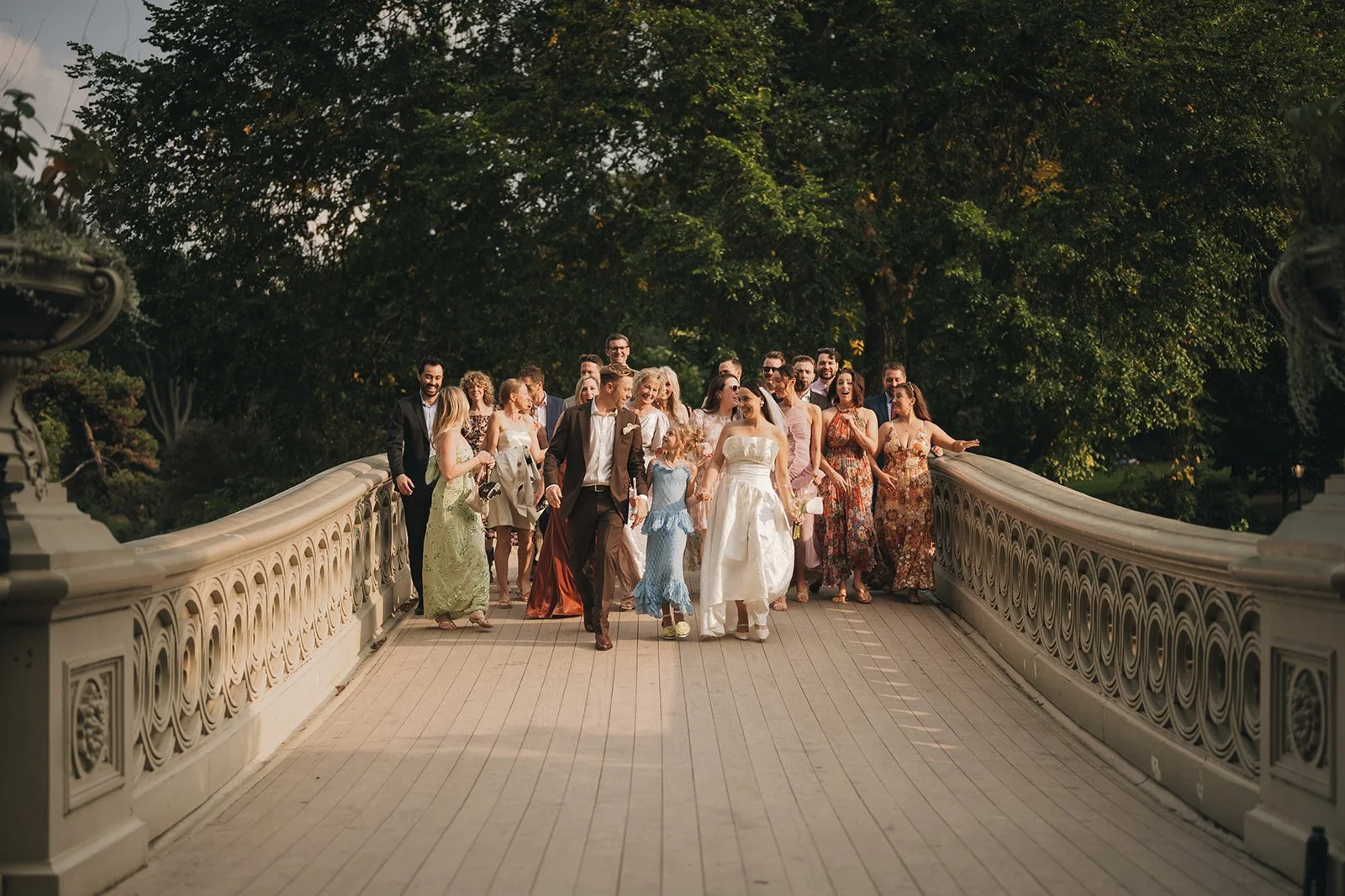 Bride, groom, and guests walking across Bow Bridge after a Cakewalk elopement ceremony in Central Park.