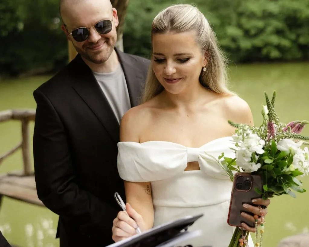 Couple signs their marriage license in Wagner Cove in Central Park with the help of their Cakewalk Officiant and day of wedding coordinator.