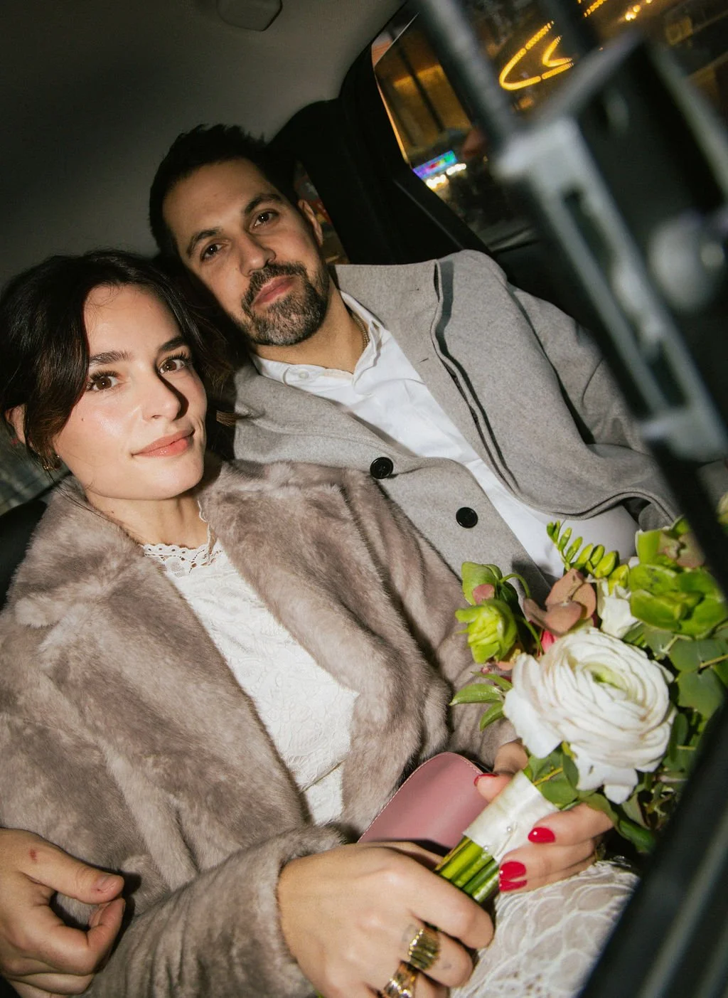 Newly married couple in a New York yellow taxi holding a bouquet after their Cakewalk elopement ceremony.