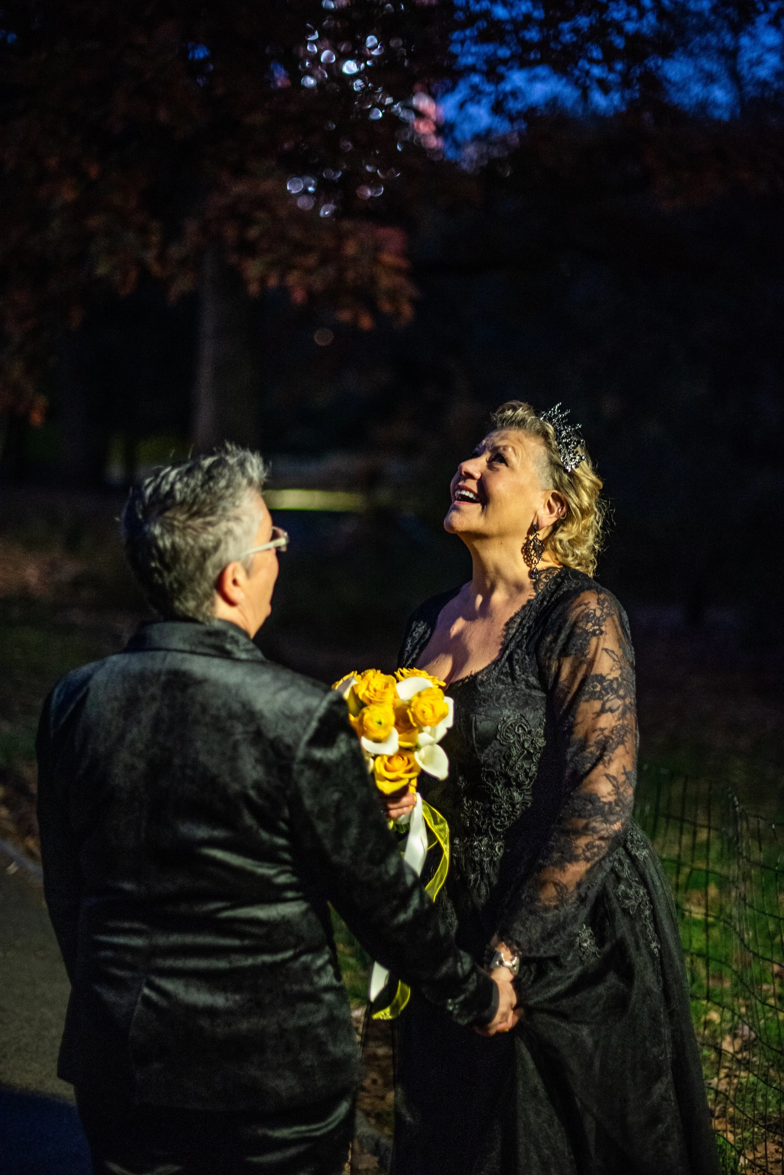 Two brides staring up at a street lamp in Central Park at night after their LGBTQ-friendly Cakewalk elopement.