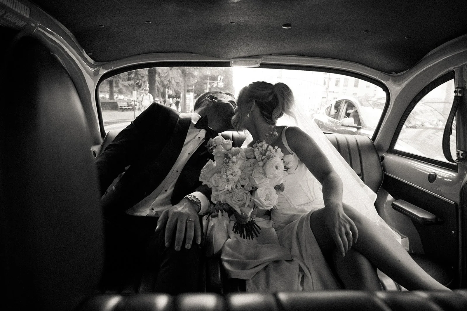 Bride and groom kissing inside the back seat of a vintage, yellow checkered NYC taxi after their Cakewalk wedding ceremony.