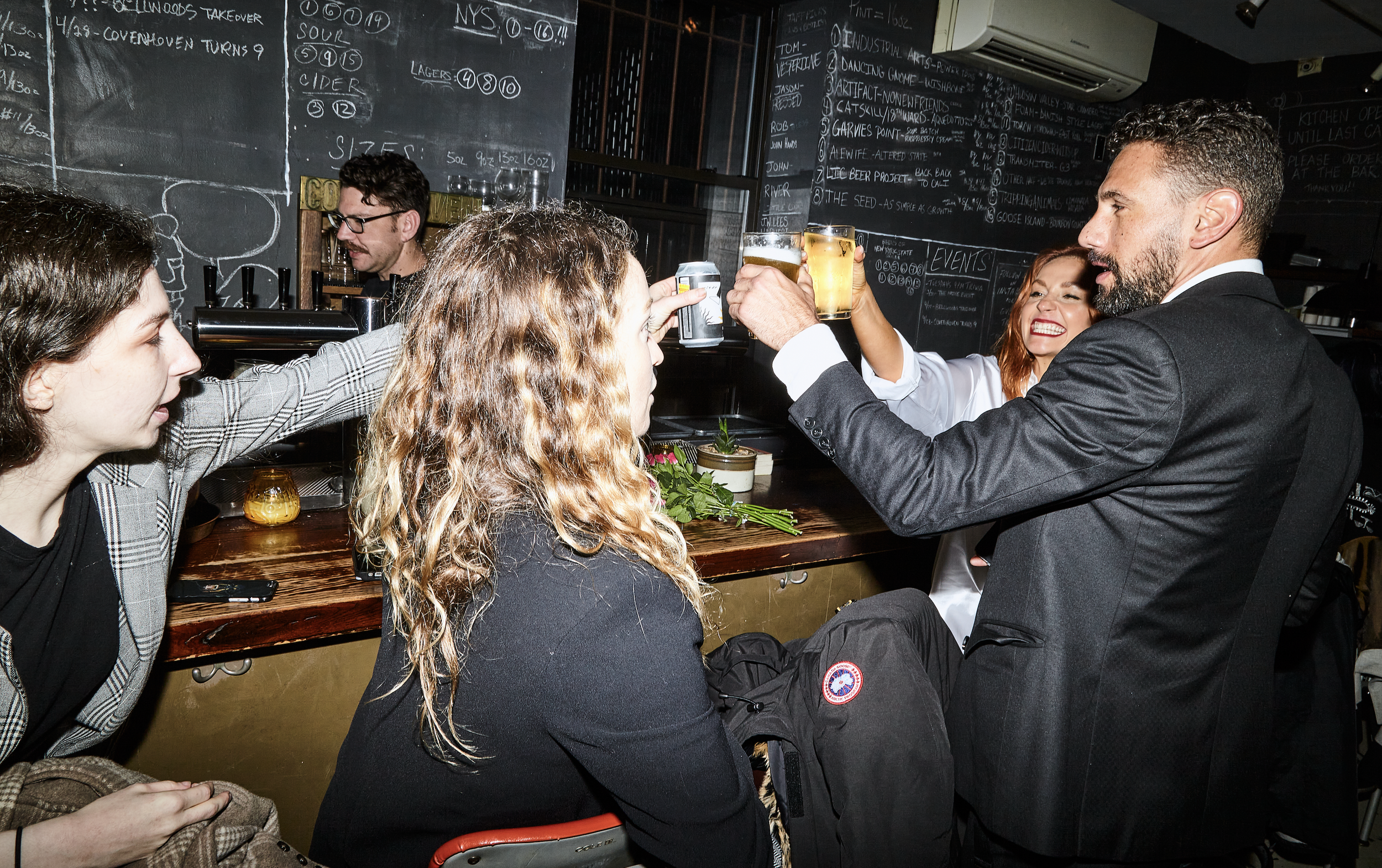 Bride and groom smiling and clinking beers with bar customers after their Cakewalk elopement ceremony.